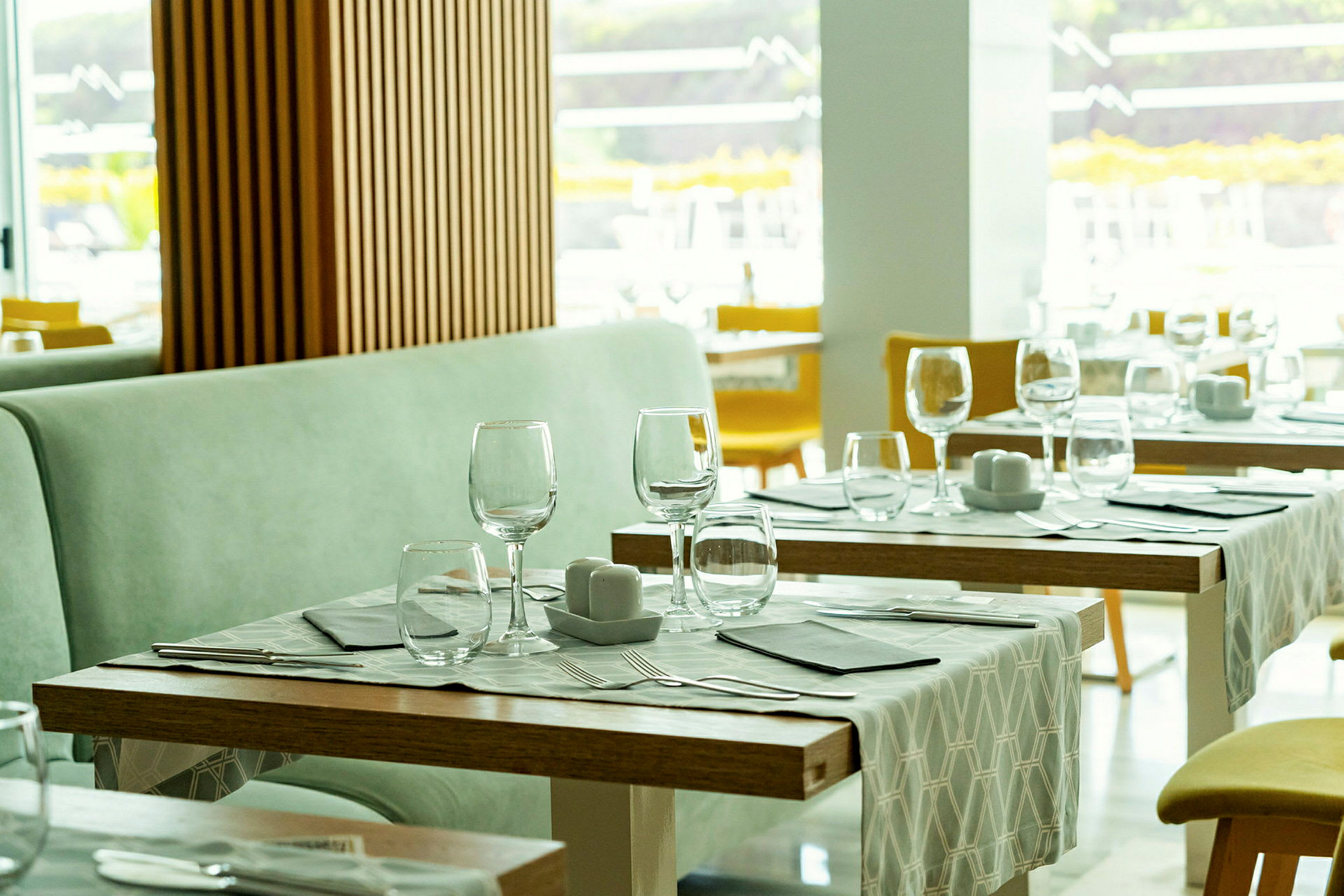 Restaurant med dekkede bord, glass og bestikk. (AI-generert tekst)