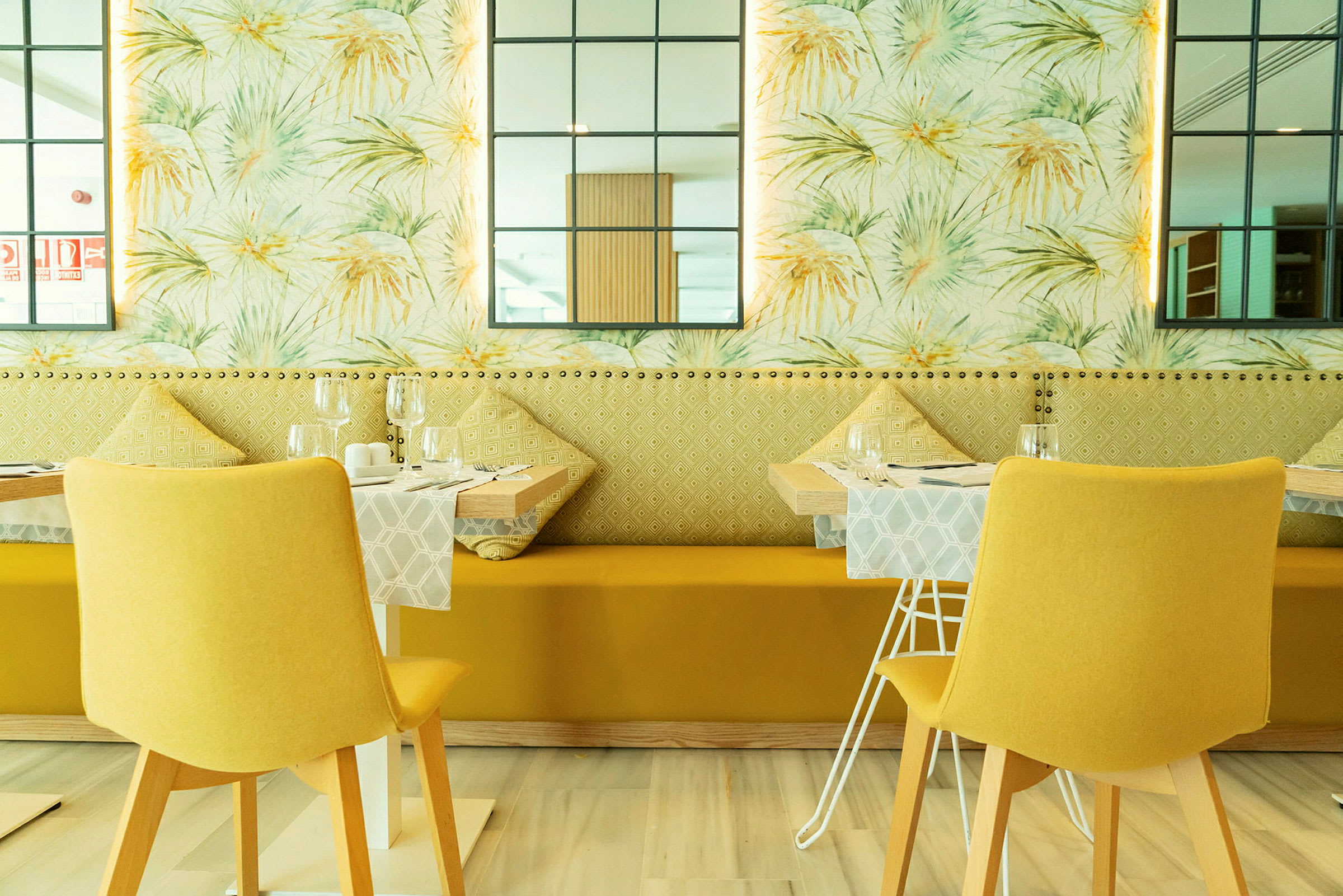 Restaurant med moderne innredning, gule stoler og dekorative veggdetaljer. (AI-generert tekst)