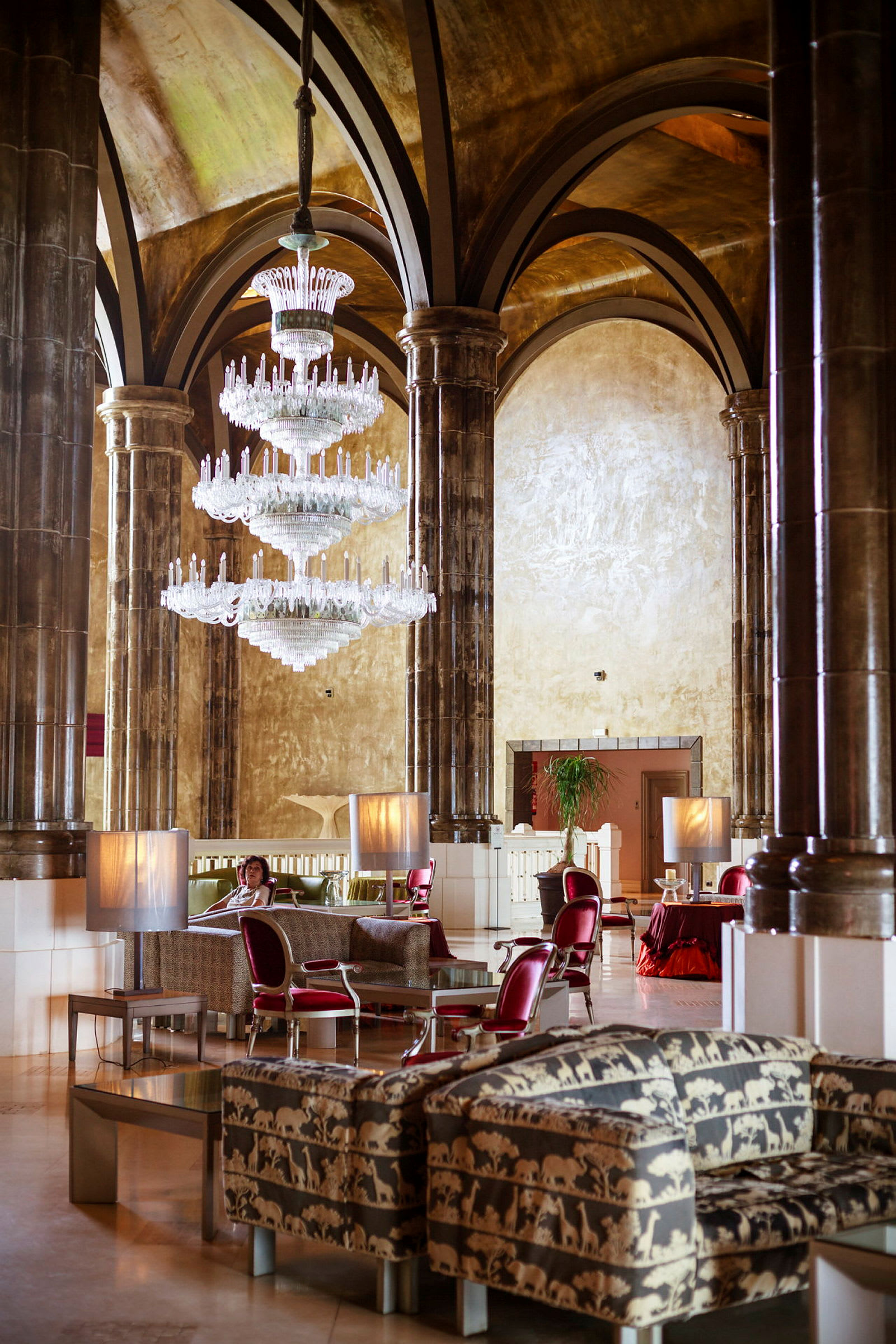 En hotellobby med luksuriøse dekorasjoner, inkludert en stor krystallkrone og møbler med dyremønstre. (AI-generert tekst)