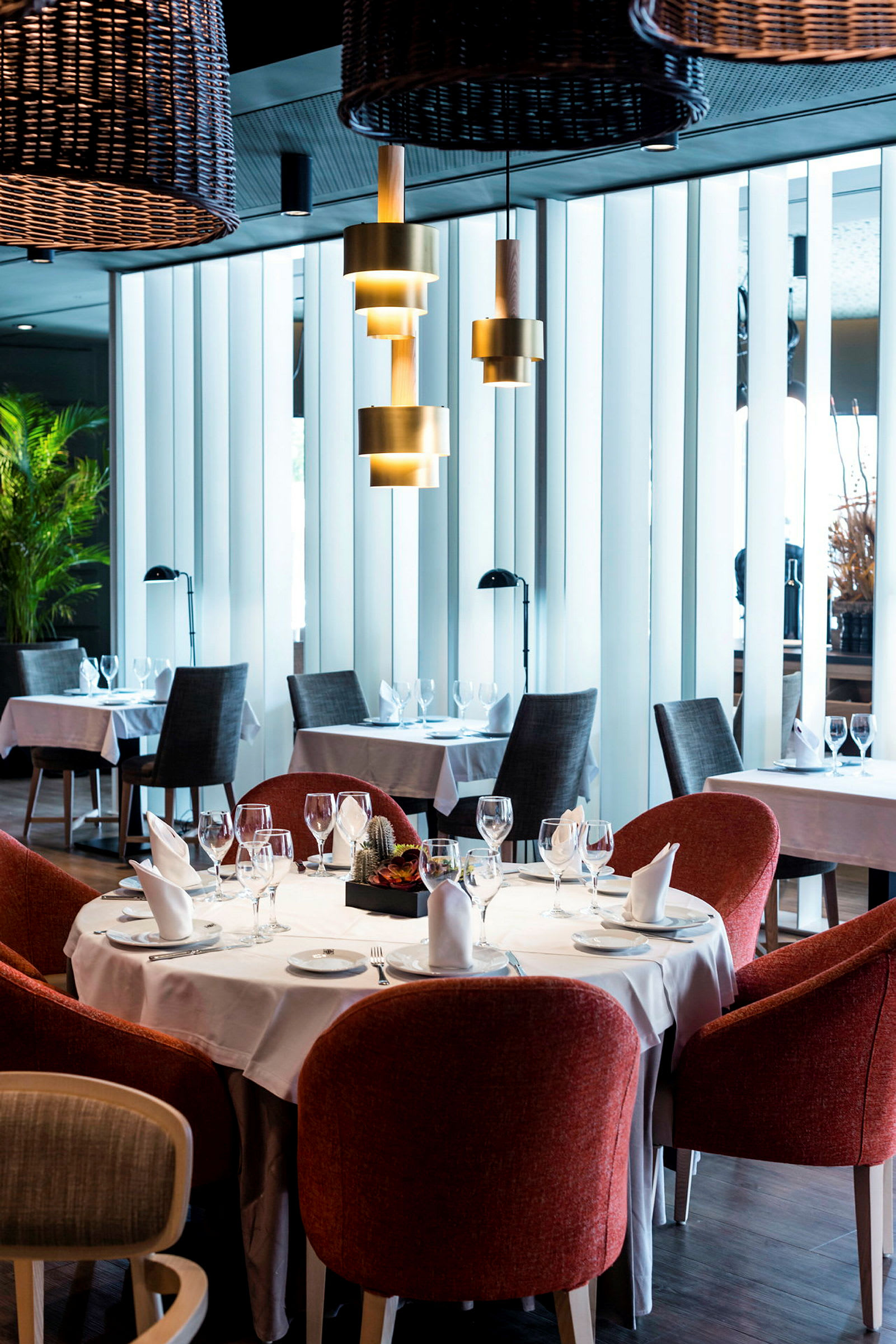 En restaurant med dekkede bord og røde stoler. (AI-generert tekst)