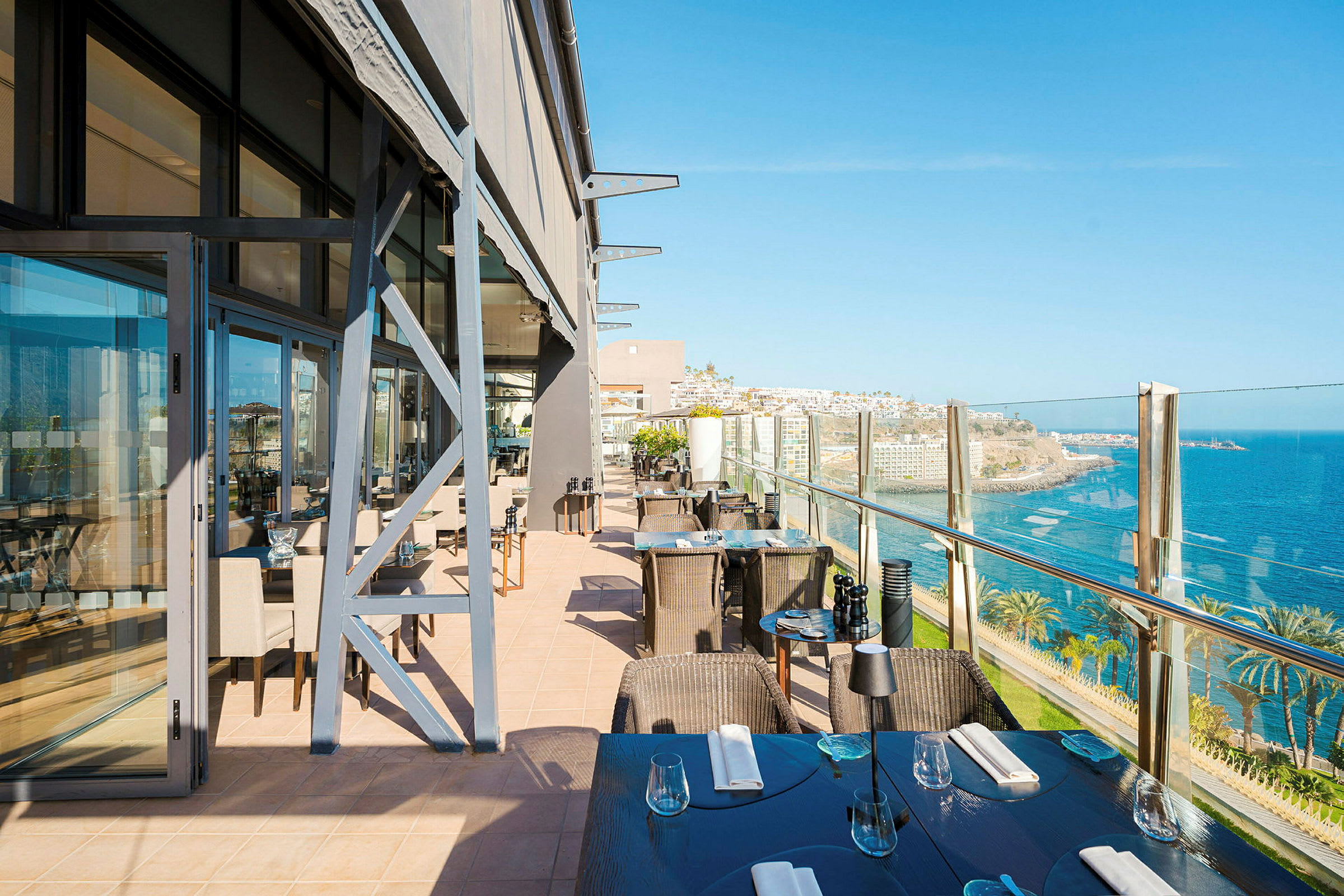 Restaurantterrasse med utsikt over havet og kystlandskapet. (AI-generert tekst)