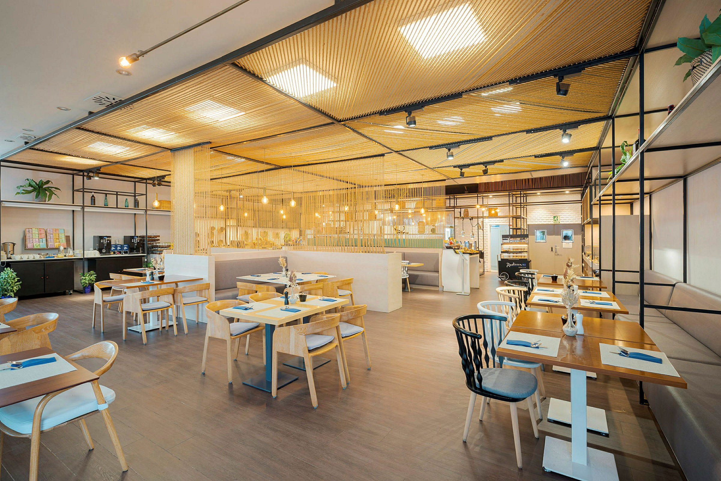 En moderne restaurant med trebord og stoler, belyst av hengende lamper. (AI-generert tekst)