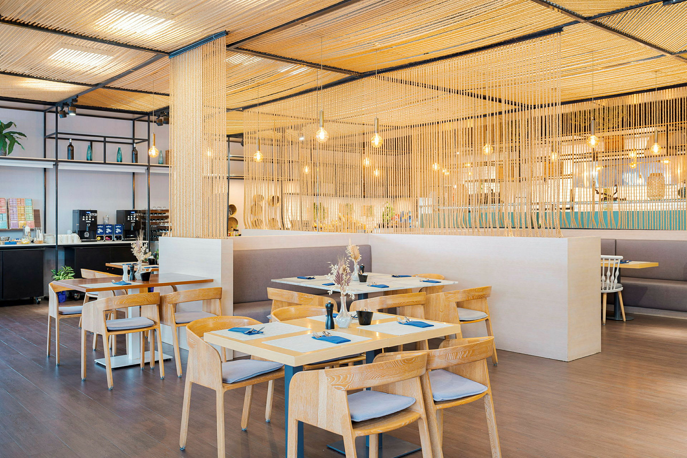 Moderne restaurant med trebord og stoler, opplyst med hengende lamper. (AI-generert tekst)