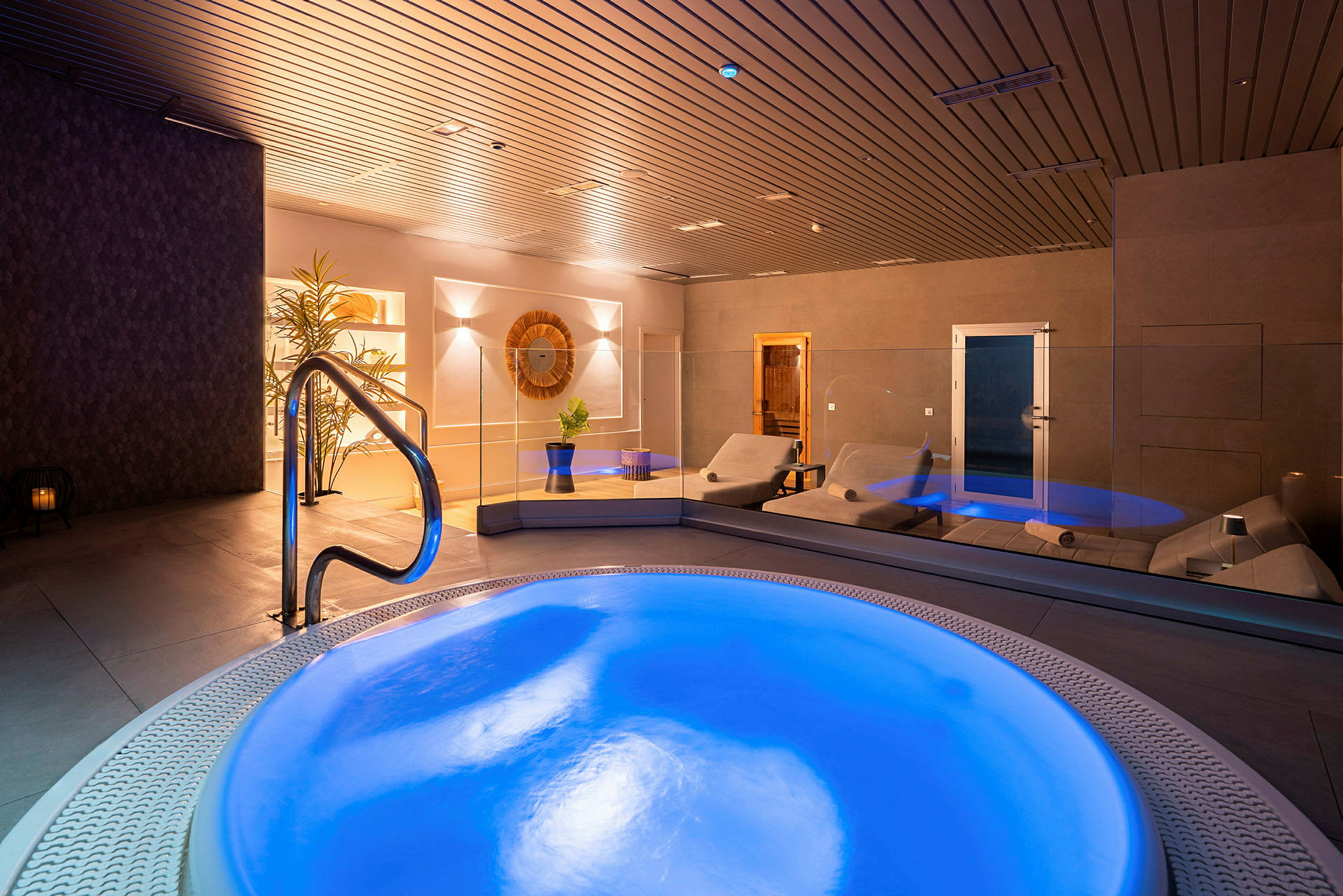 Interiør av et spa med en belyst boblebad og liggestoler. (AI-generert tekst)
