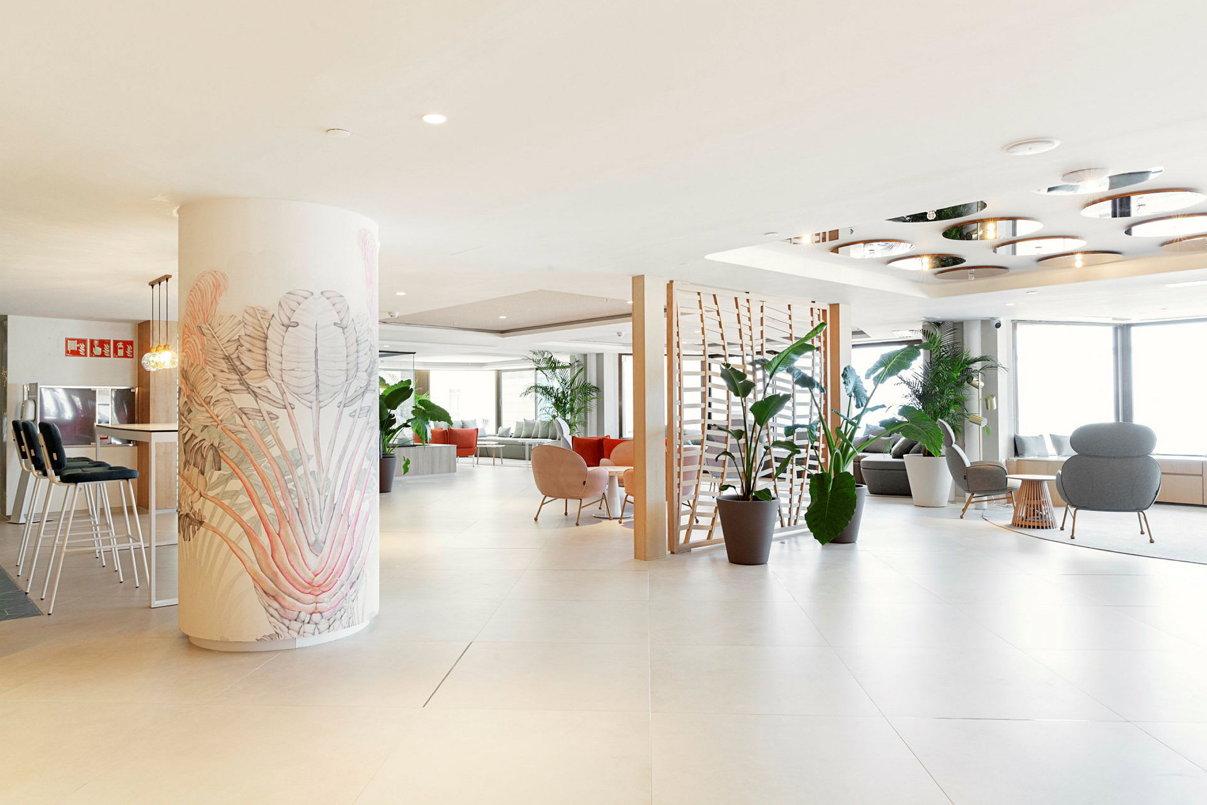 En romslig og lyst innredet hotellobby med flere sittemøbler og grønne planter. (AI-generert tekst)