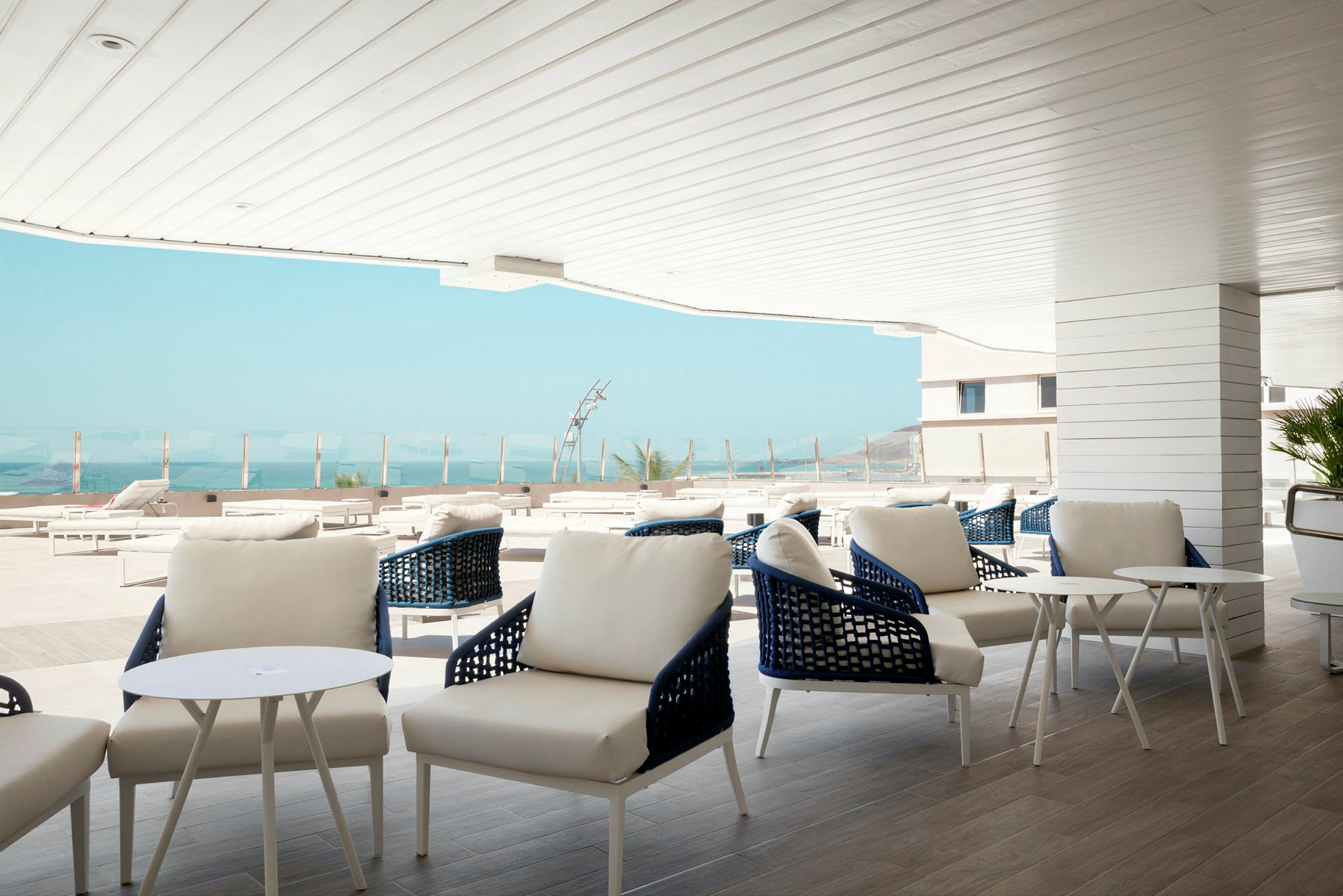Moderne utendørs lounge med hvite møbler og utsikt over havet. (AI-generert tekst)