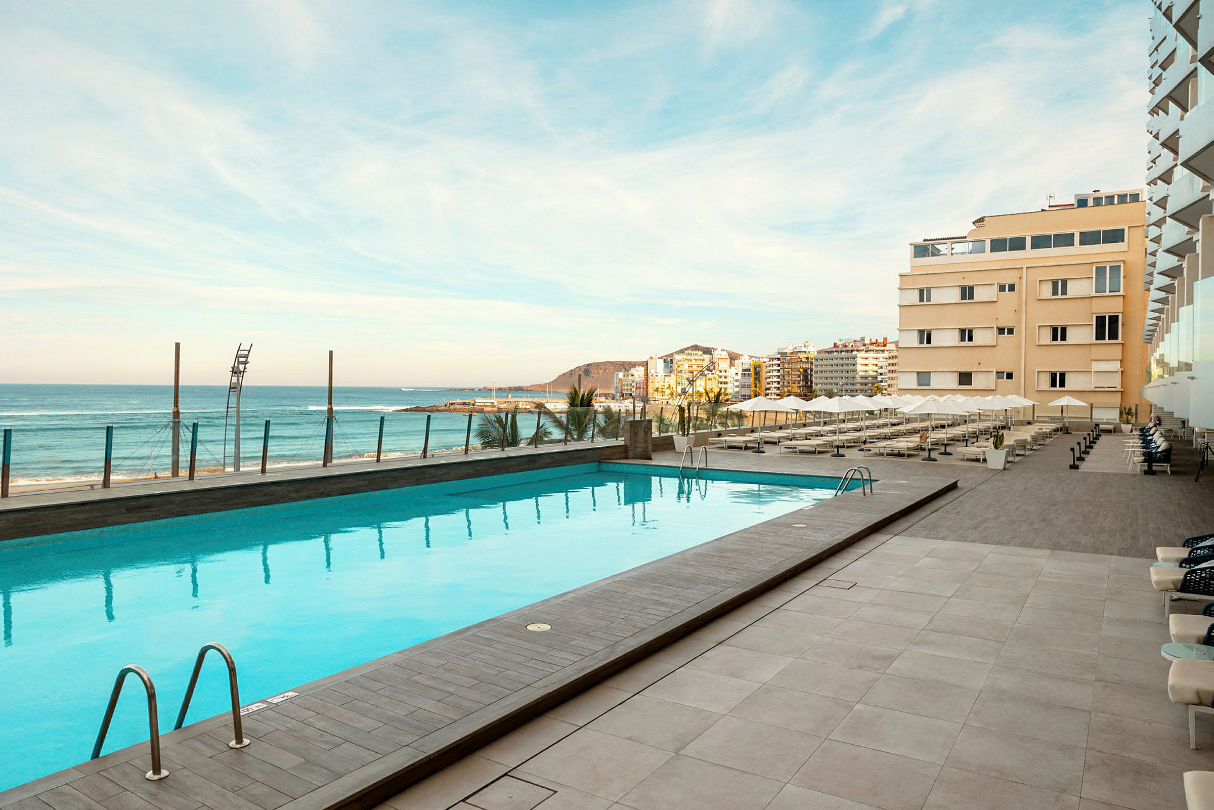 Utendørsbasseng ved hotellet, med utsikt over stranden og havet. (AI-generert tekst)