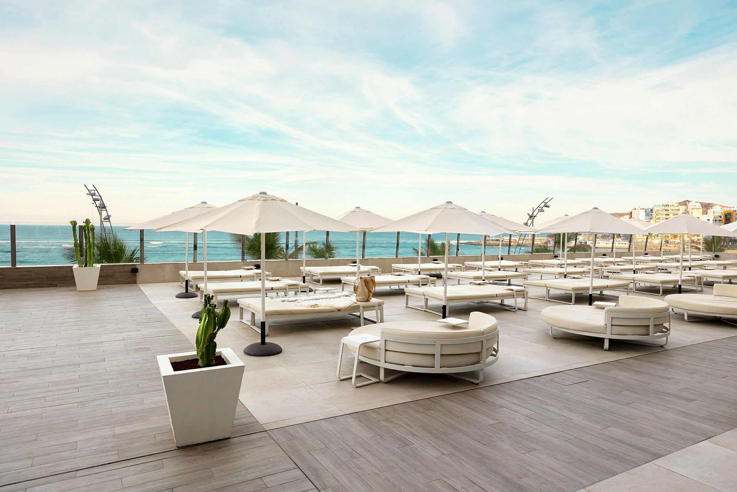 Utendørsområde med solsenger og parasoller på en romslig terrasse med utsikt over havet. (AI-generert tekst)