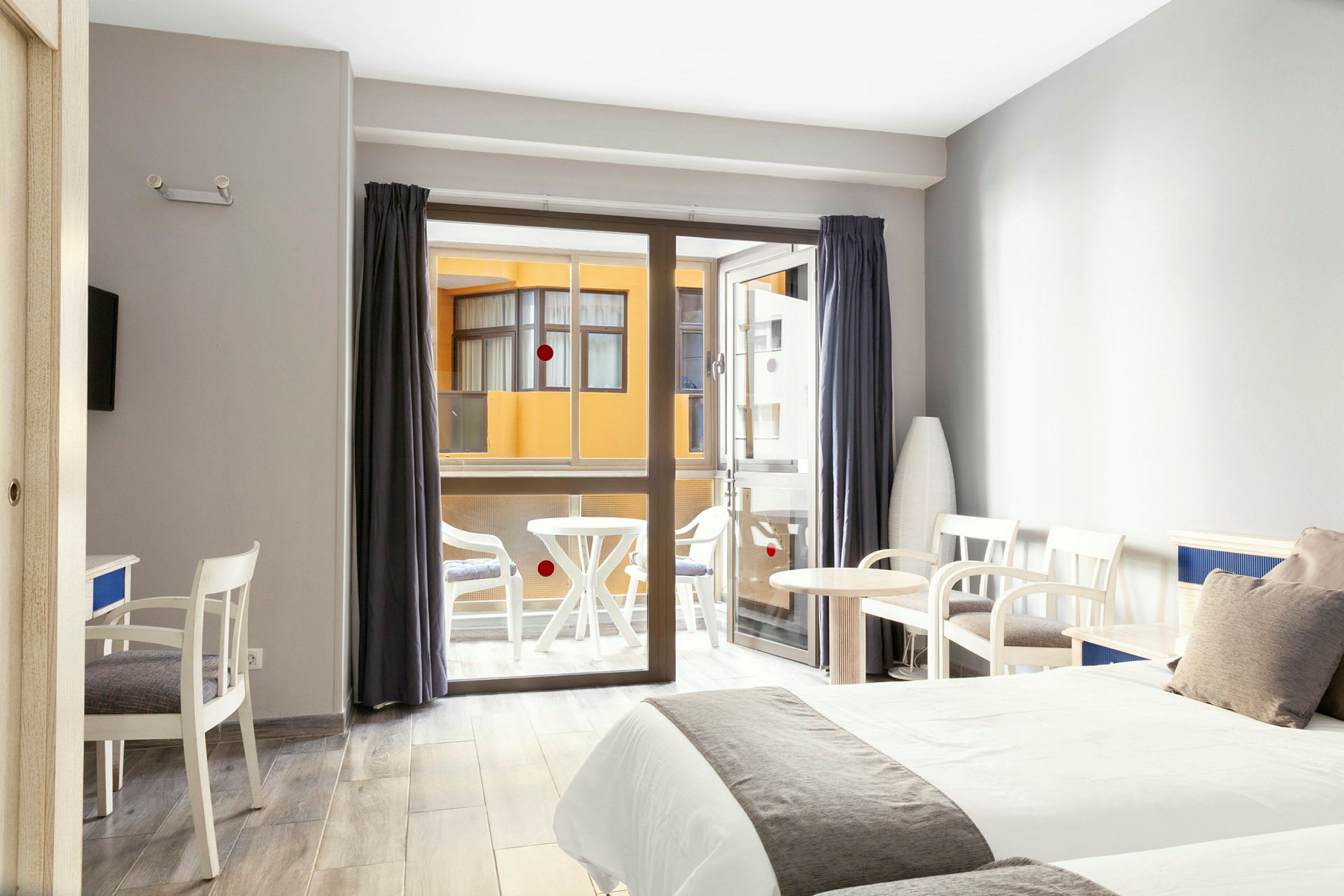 Hotellrom med to senger, sittemøbler og en balkong i bakgrunnen. (AI-generert tekst)