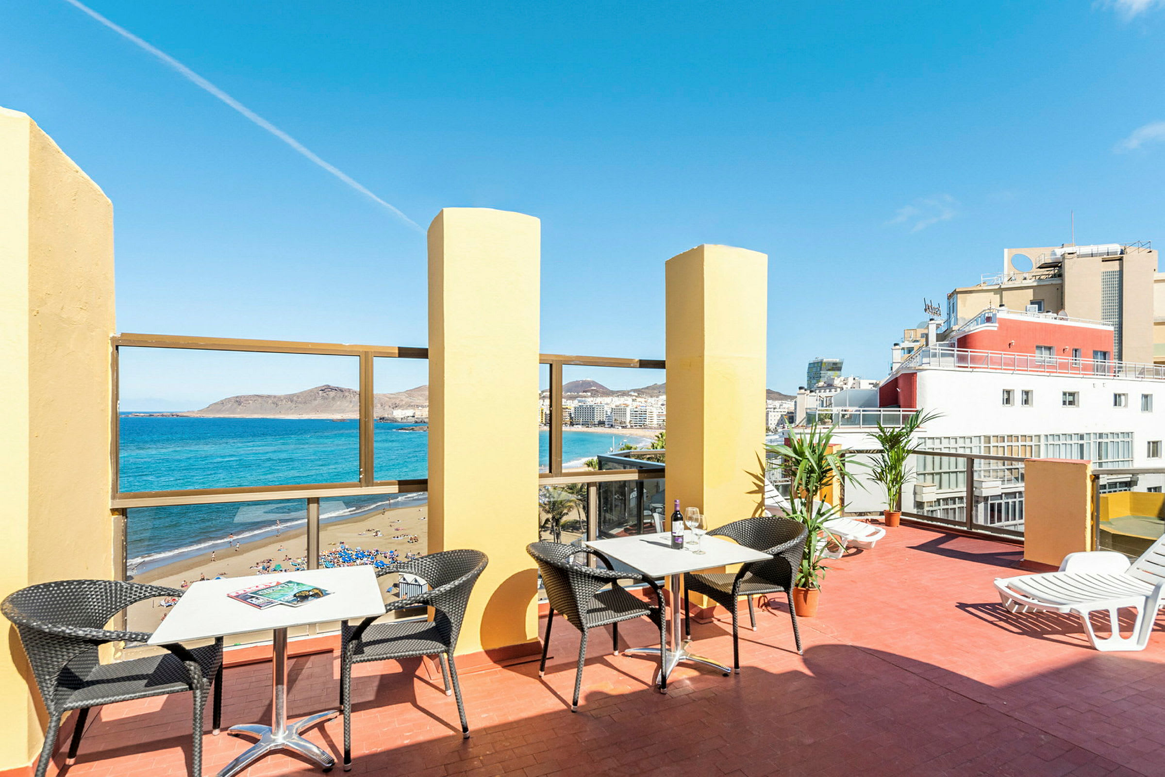 En terrasse med bord og stoler, utsikt over havet og stranden. (AI-generert tekst)