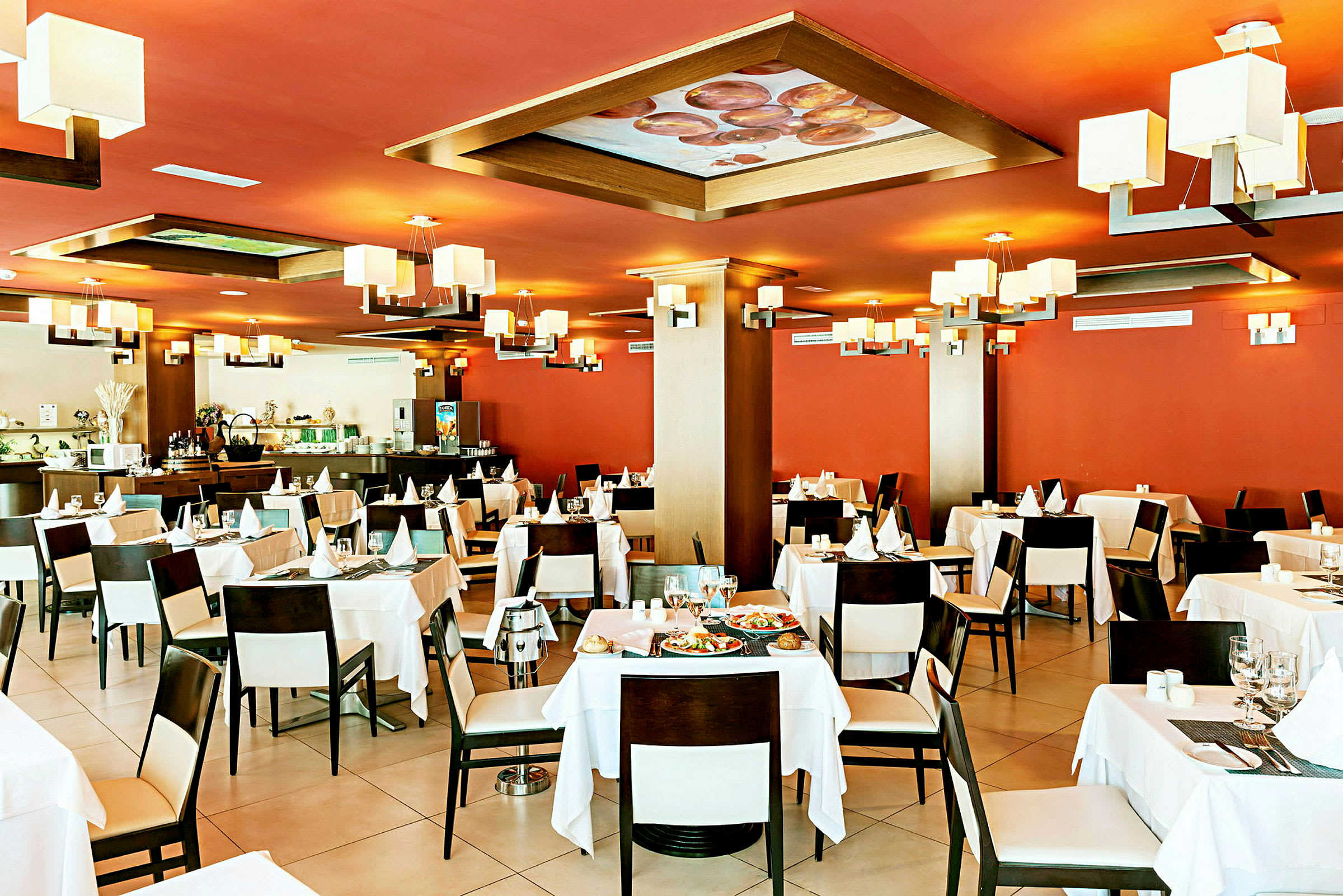 Interiør av en restaurant med røde vegger, hvite duker og moderne belysning. (AI-generert tekst)