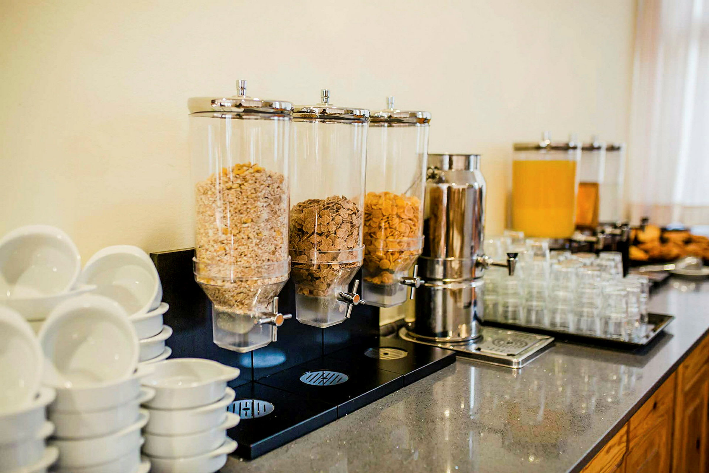 Bilde av frokostbuffé med frokostblandingsautomater, drikkebeholdere og kopper. (AI-generert tekst)