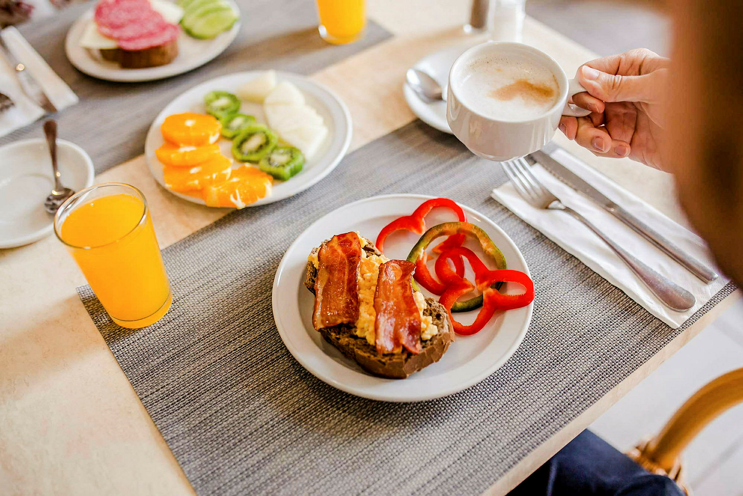 En anrett frokost med brødskive, paprika, frukt, appelsinjuice og en kopp kaffe. (AI-generert tekst)