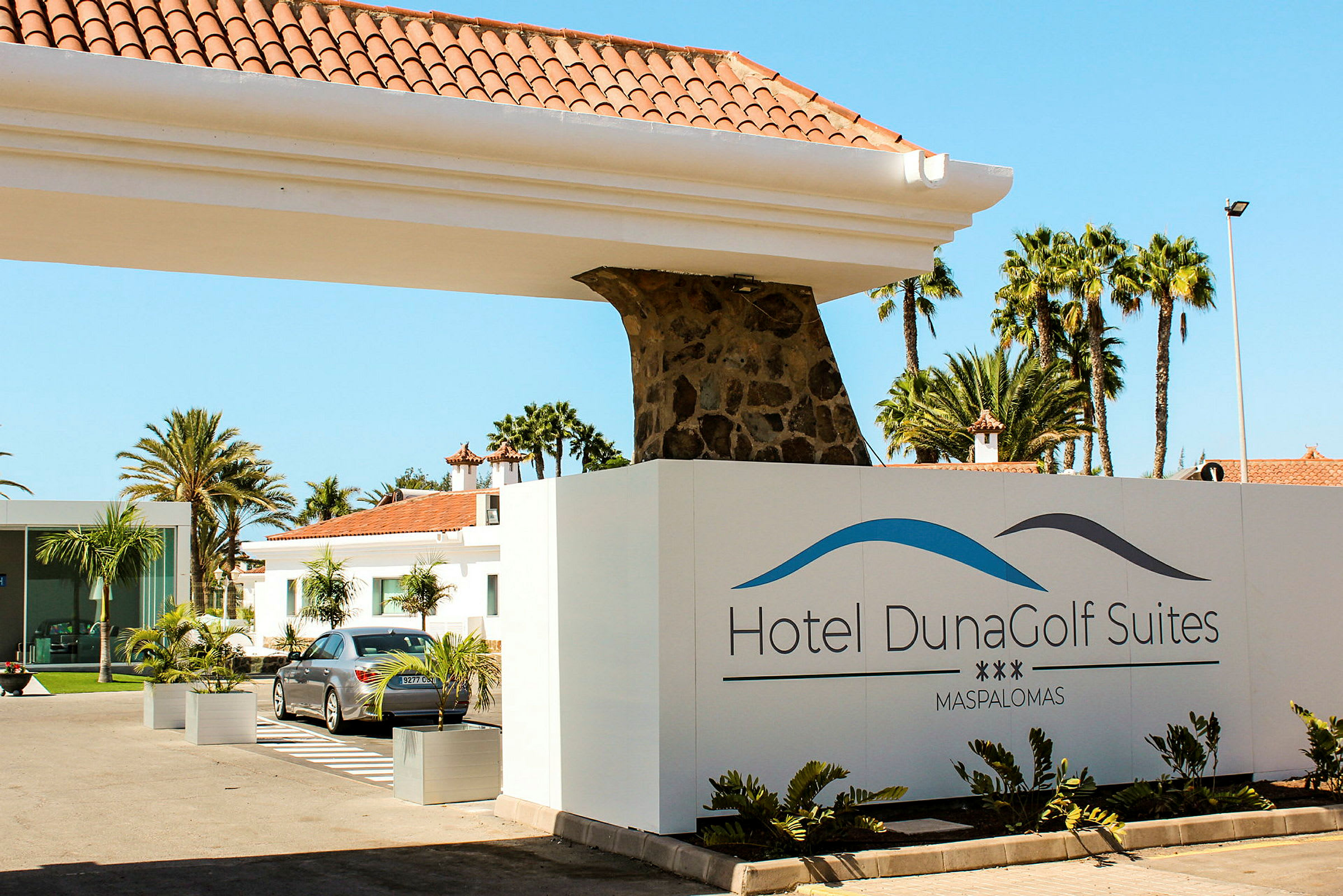 Inngangen til Hotel DunaGolf Suites med skilt og bygninger i bakgrunnen. (AI-generert tekst)