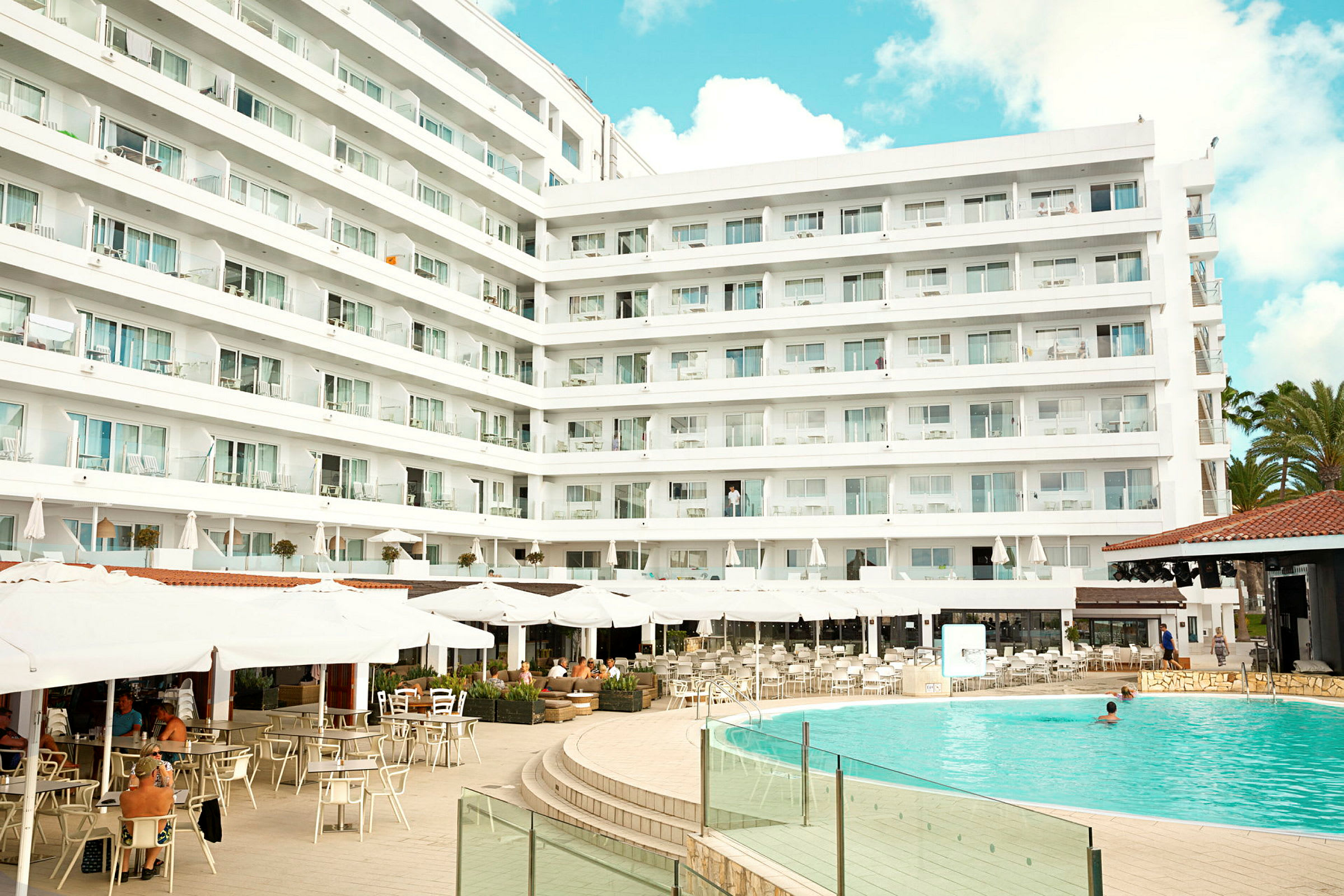 Hotellkompleks med basseng og uteservering. (AI-generert tekst)