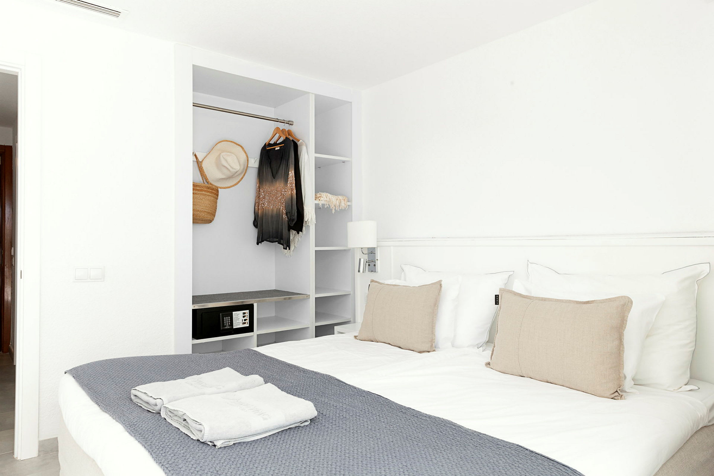 Et hotellrom med en dobbeltseng og en åpen garderobe. (AI-generert tekst)