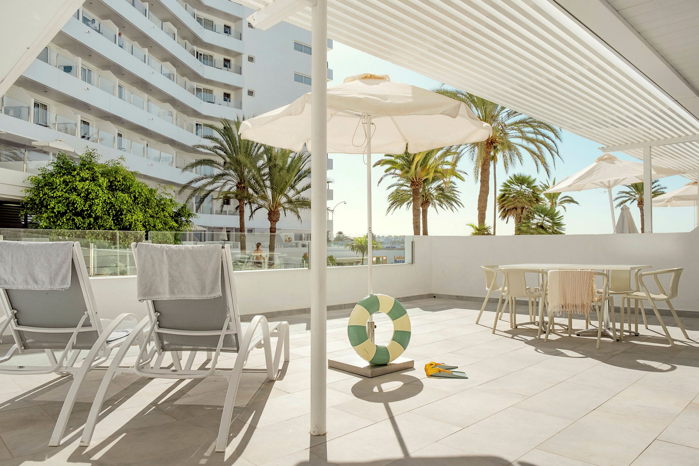Solstoler på en solrik terrasse med parasoller og palmer i bakgrunnen. (AI-generert tekst)