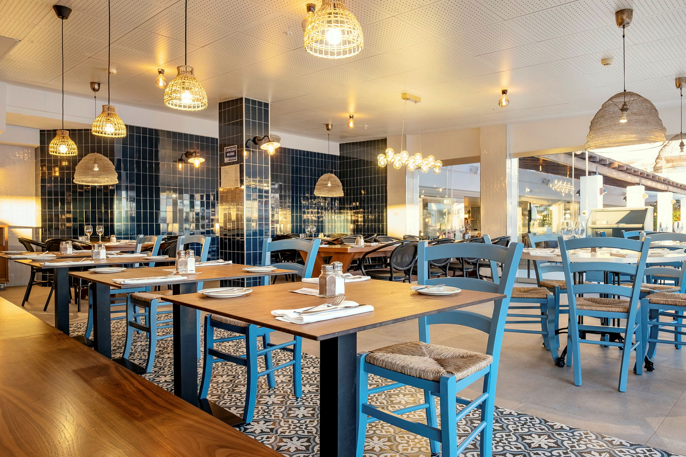 En restaurant med bord og blå stoler. (AI-generert tekst)