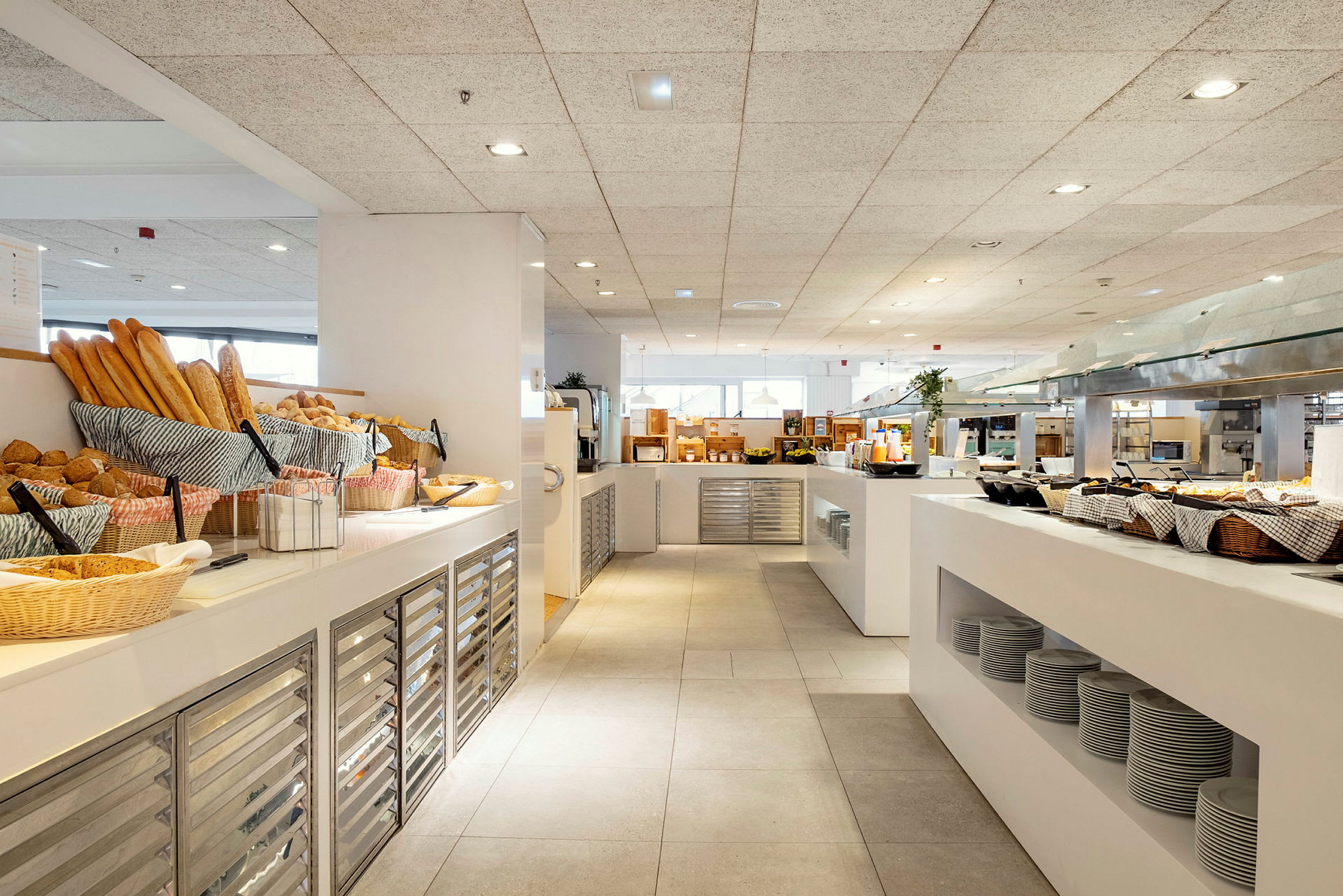 Frokostbuffé på et hotell med ferskt brød, tallerkener og serveringsstasjoner. (AI-generert tekst)