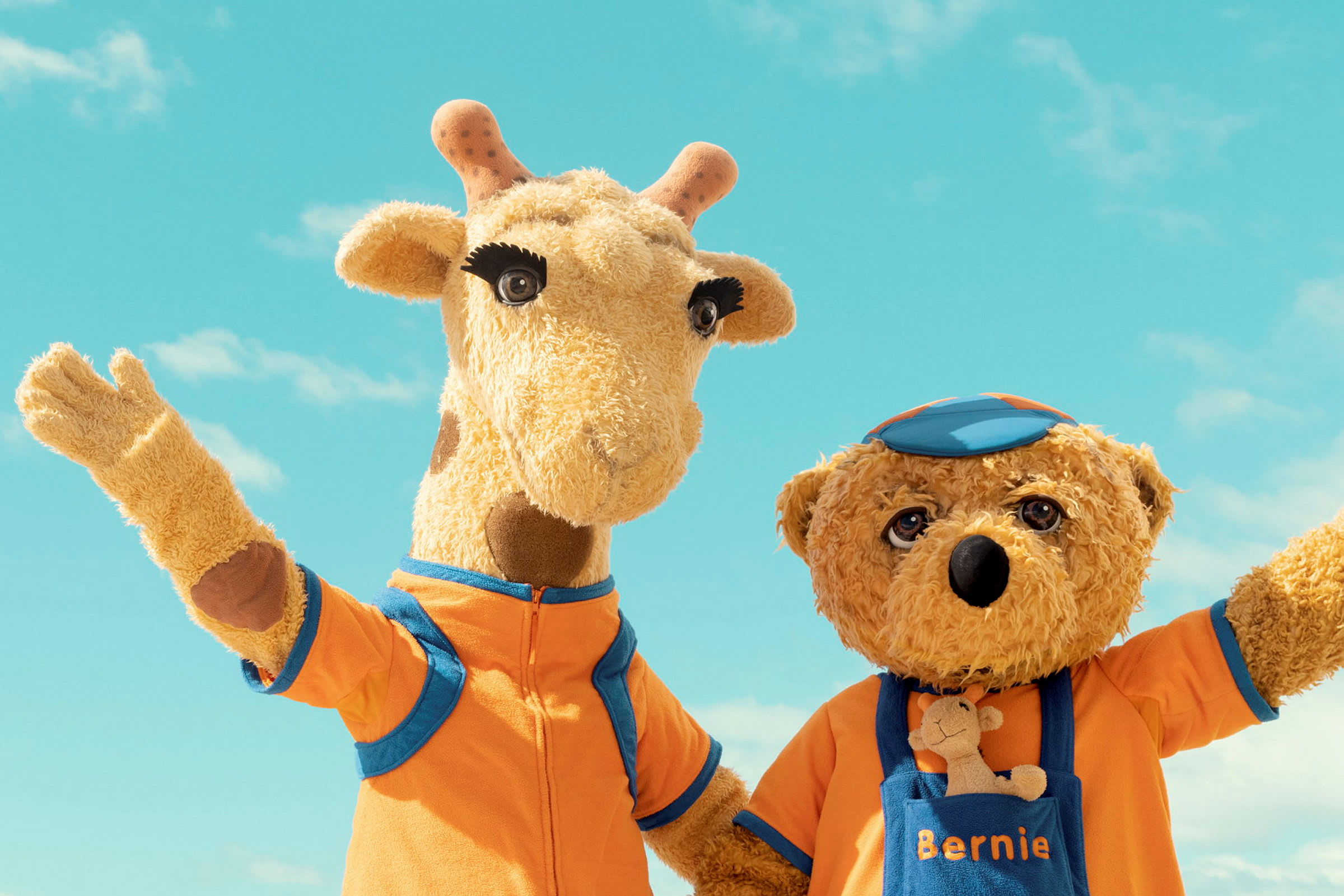 To kosedyr, en giraff og en bjørn, poserer sammen foran en blå himmel. (AI-generert tekst)