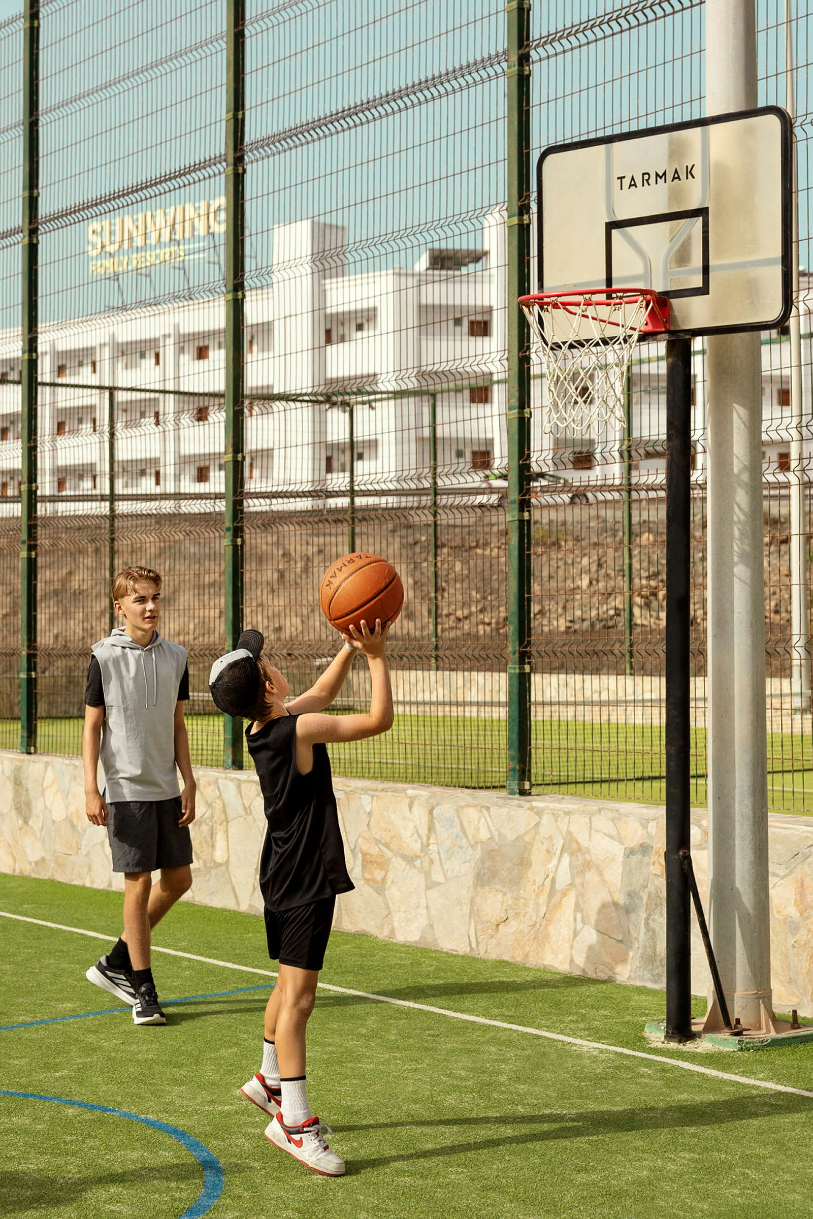 En person spiller basketball utendørs mot et nett med en ball. (AI-generert tekst)