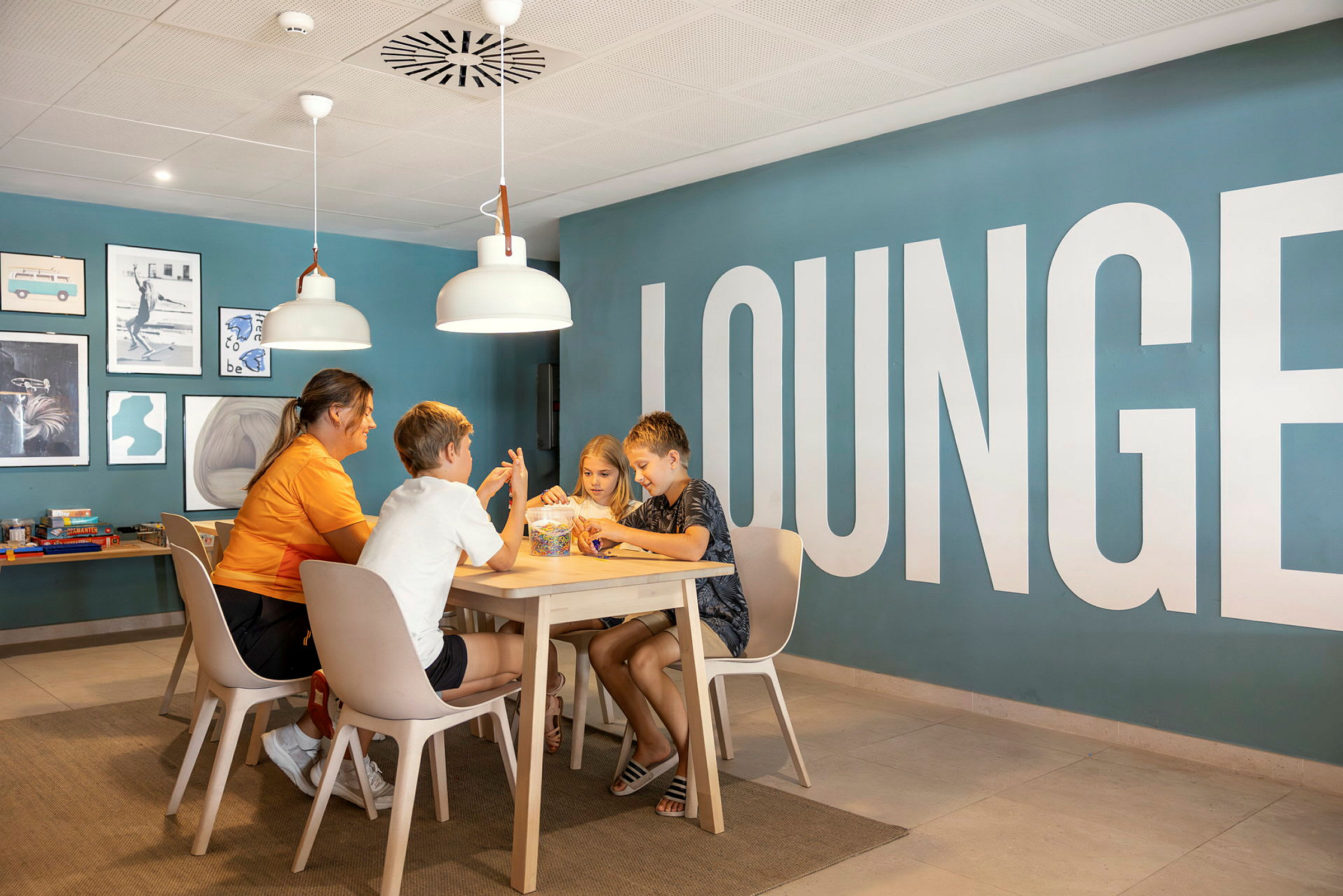 En gruppe personer sitter ved et bord i en lounge med blå vegger og dekorativ kunst. (AI-generert tekst)