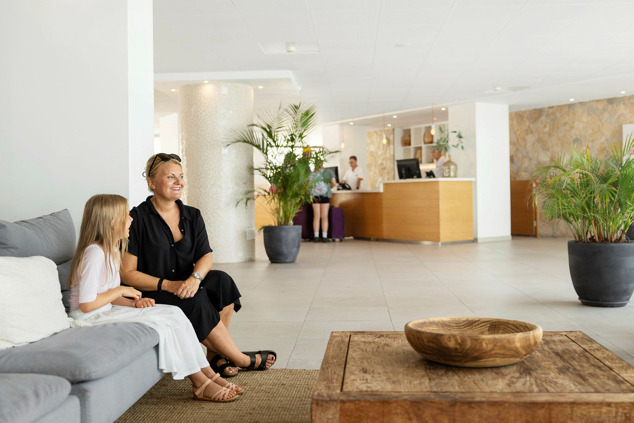 Hotellobby med sofaer, bord og resepsjon. (AI-generert tekst)