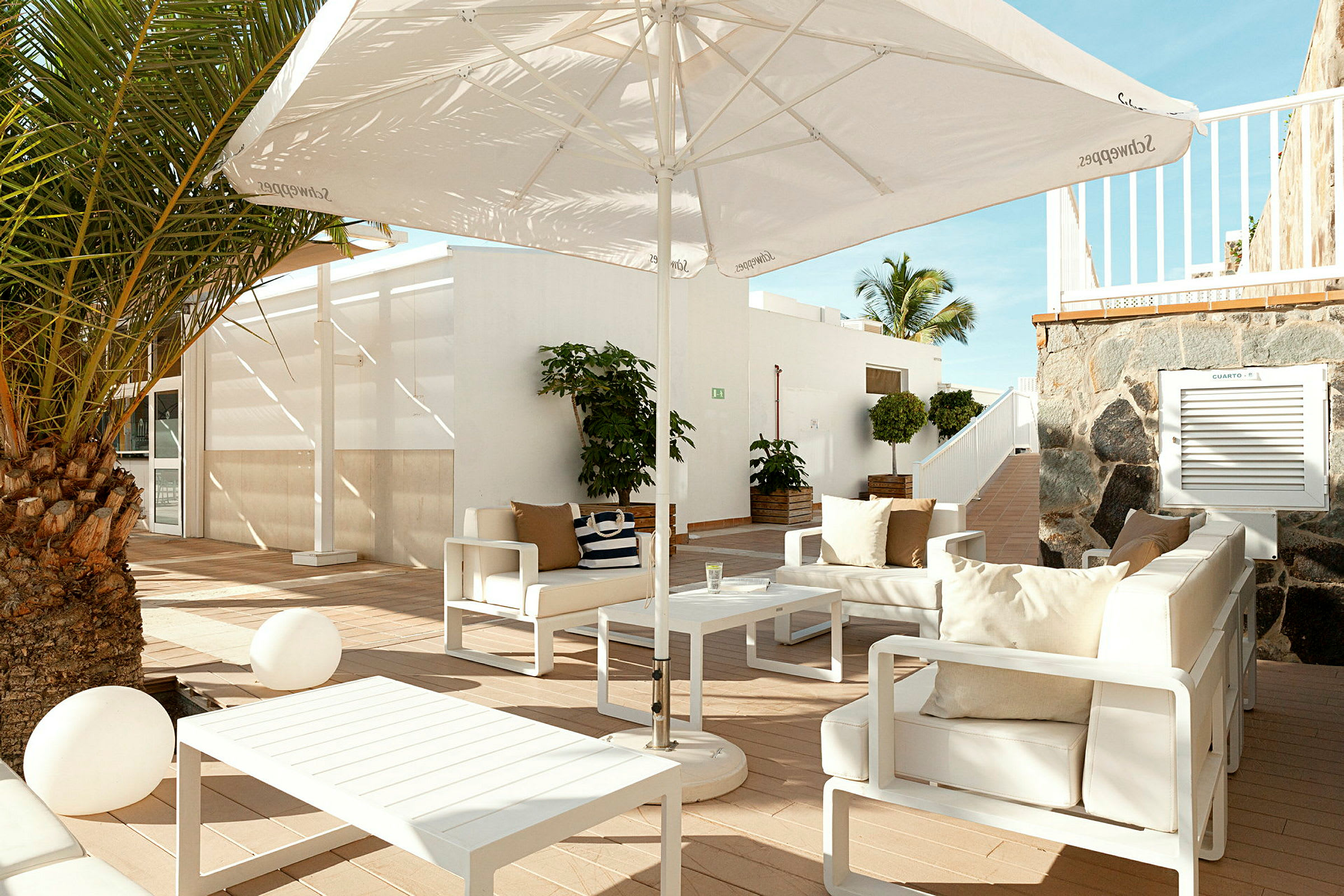 Utendørs loungemøbler med sofaer, parasoll og et bord på en terrasse. (AI-generert tekst)