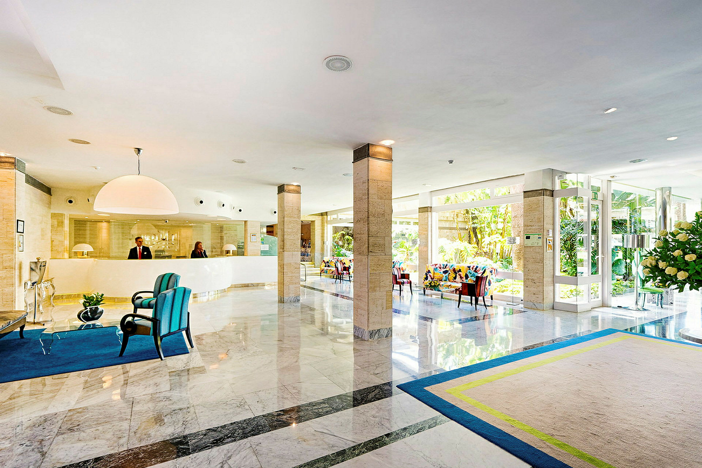 Lys hotellobby med resepsjon, sittemøbler og glassdører. (AI-generert tekst)