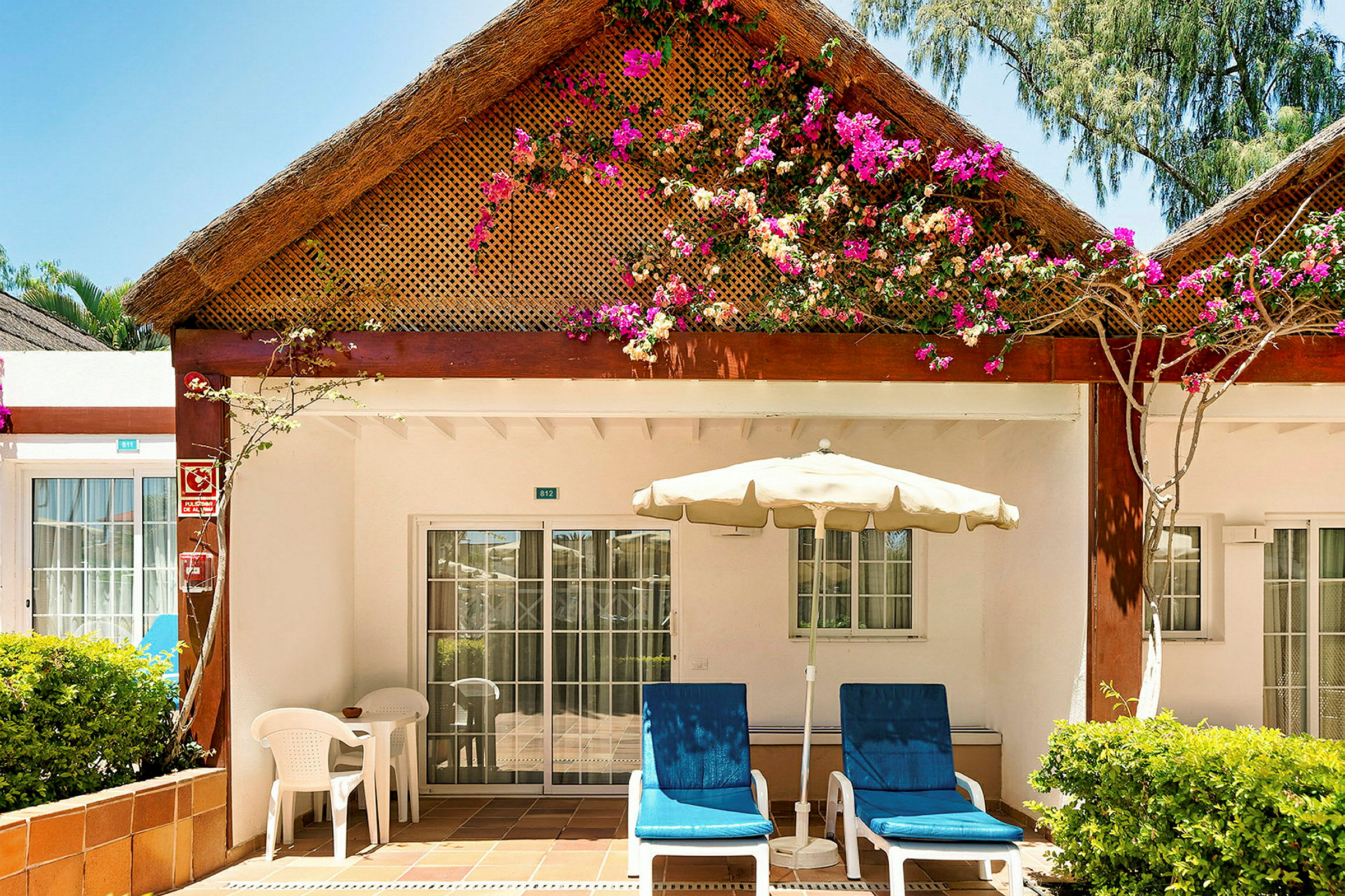 En terrasse ved en bungalow med blomster på taket. (AI-generert tekst)