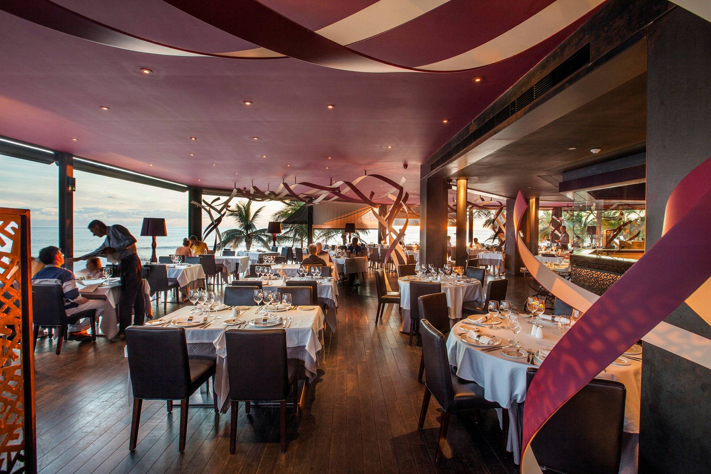 En elegant restaurant med dekkede bord og havutsikt. (AI-generert tekst)
