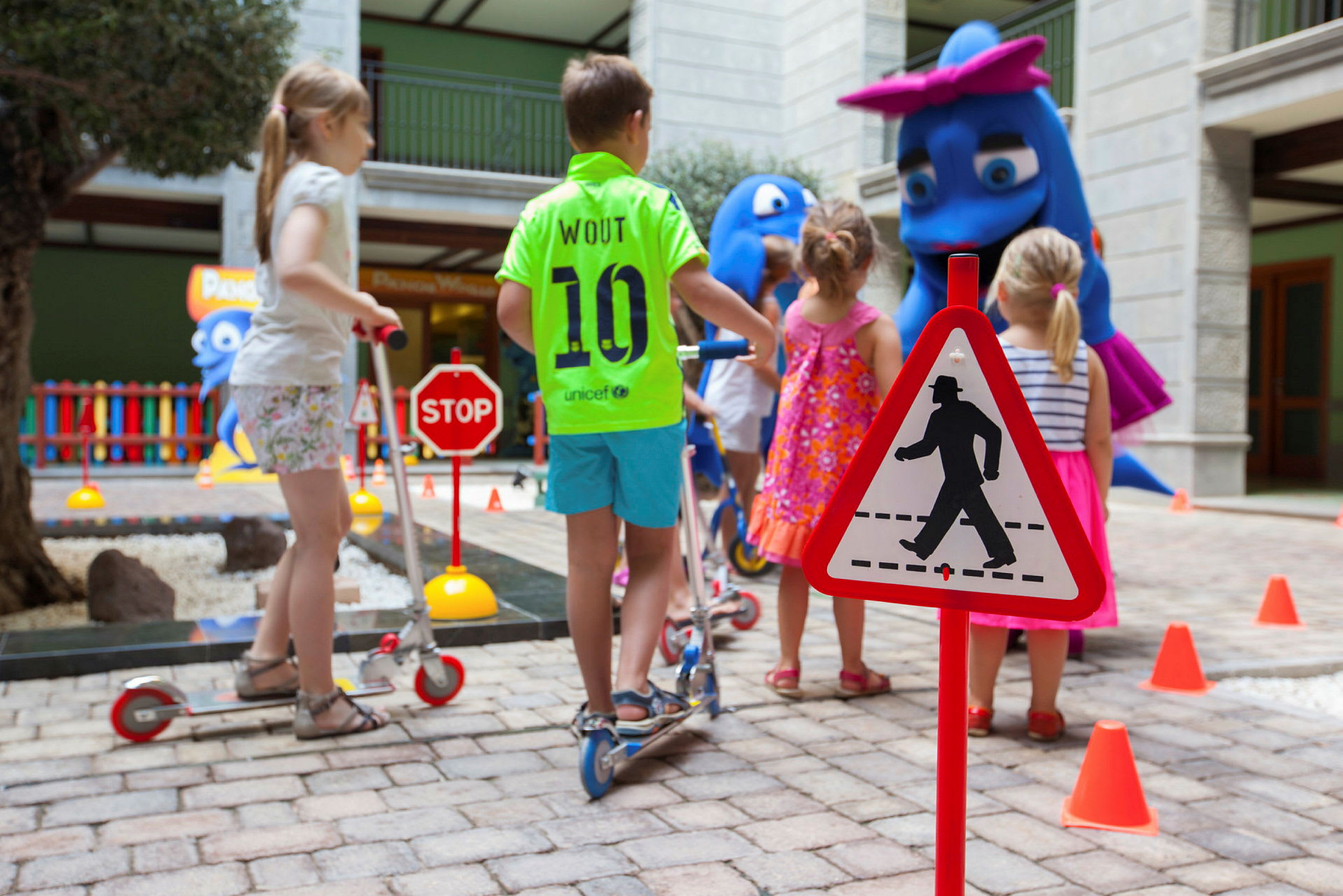 Barn leker i en innendørs bane med trafikkskilt og figurer. (AI-generert tekst)