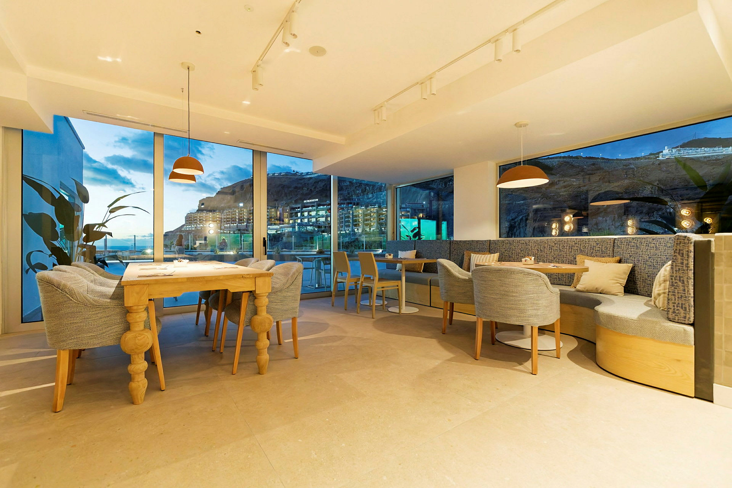 Bilde av en moderne restaurant med store vinduer og utsikt over kveldslandskapet. (AI-generert tekst)