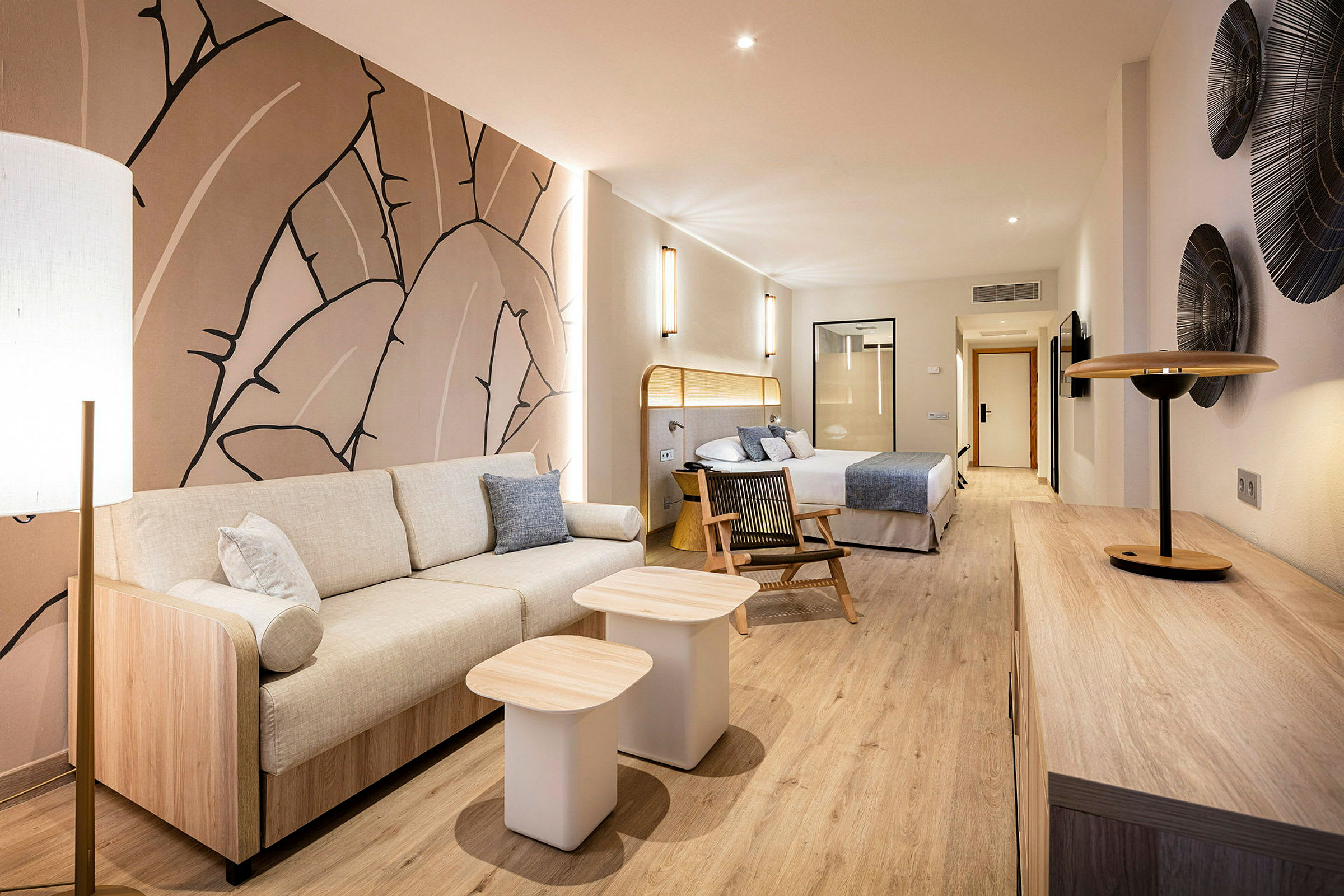 Moderne hotellsuite med sittegruppe, seng og dekorativ kunst på veggen. (AI-generert tekst)