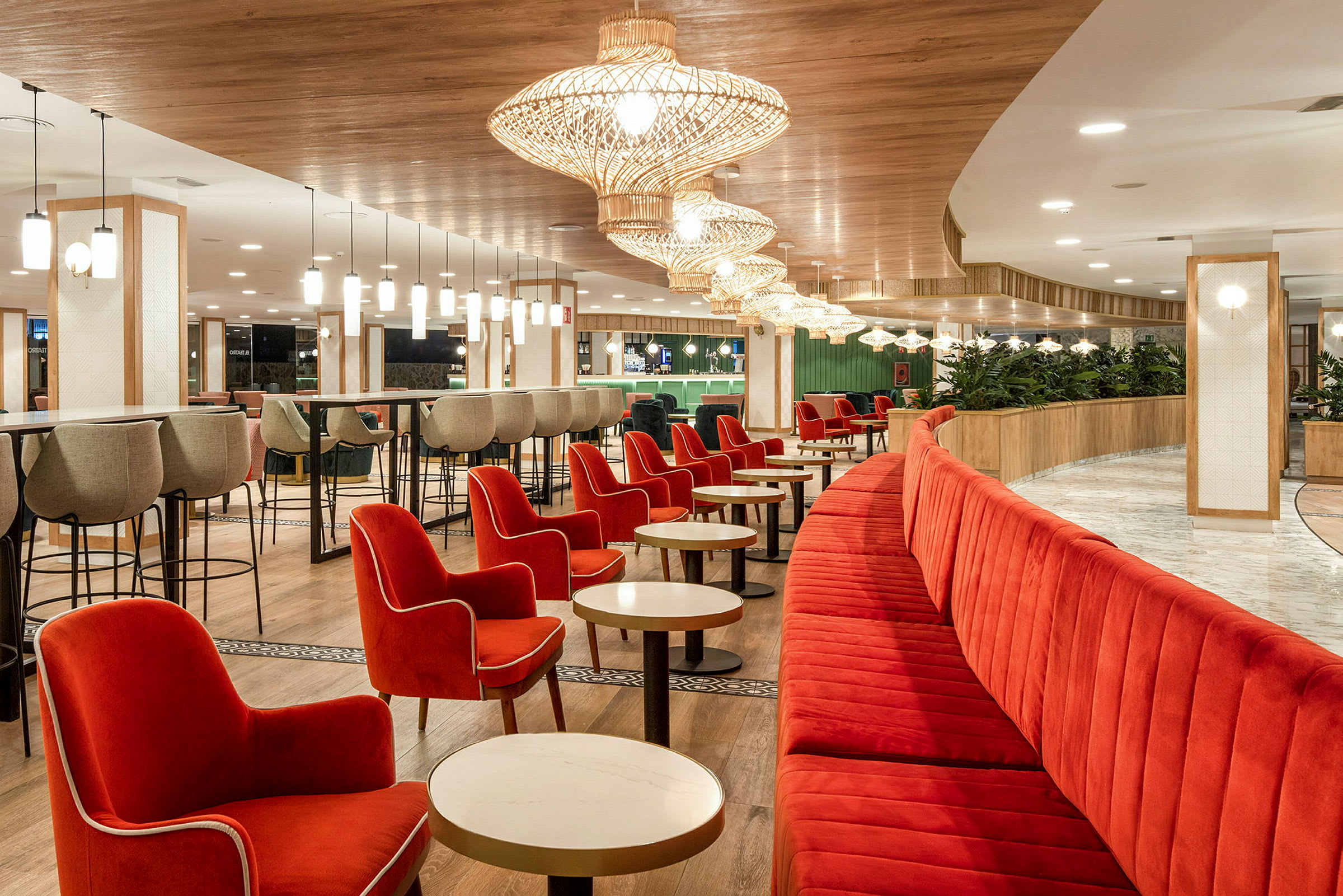 En restaurant med røde lenestoler og benker, lyse bord og moderne taklamper. (AI-generert tekst)
