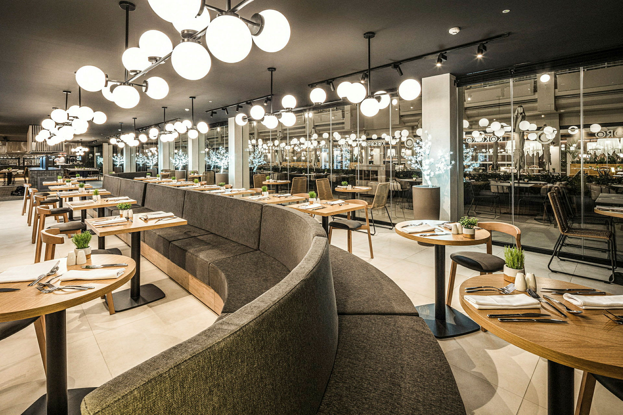 Moderne restaurantmiljø med buet sitteområde og runde bord, elegant dekorert. (AI-generert tekst)