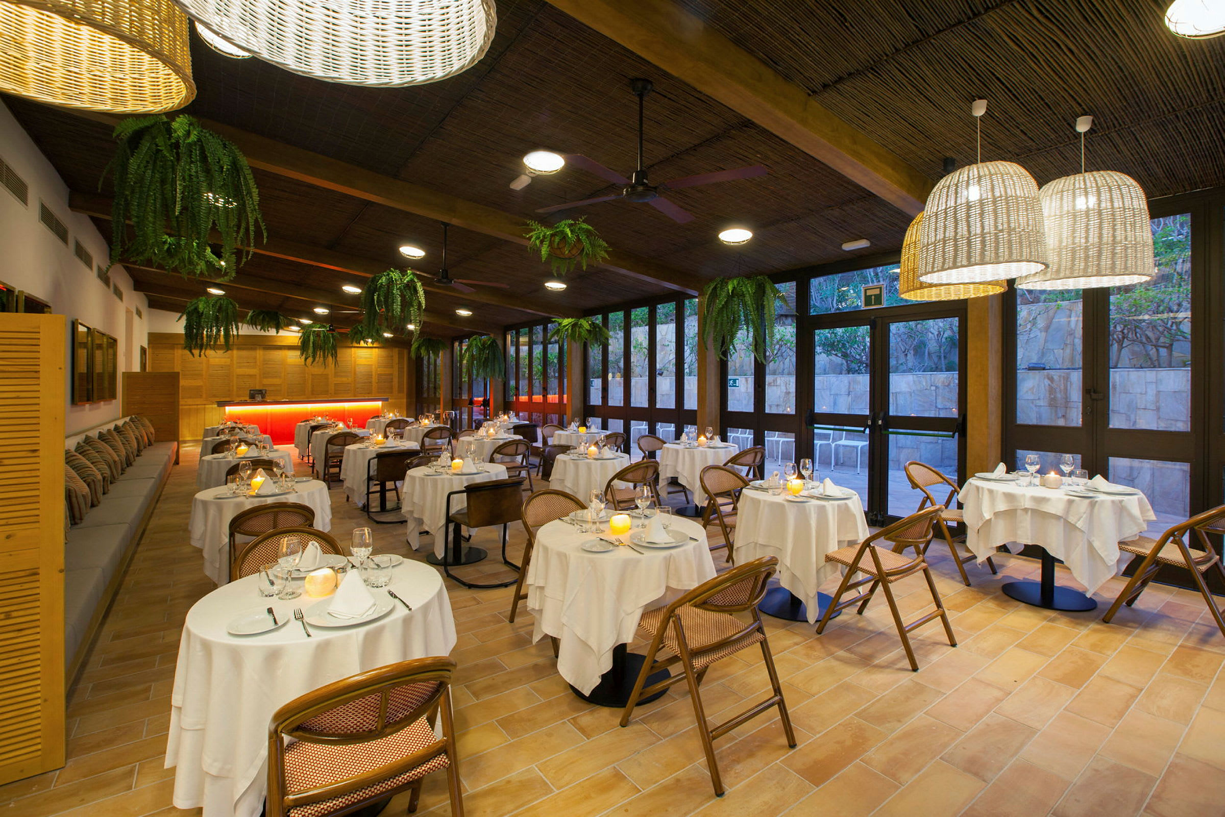 En restaurant med runde bord, hvite duker og stoler. (AI-generert tekst)
