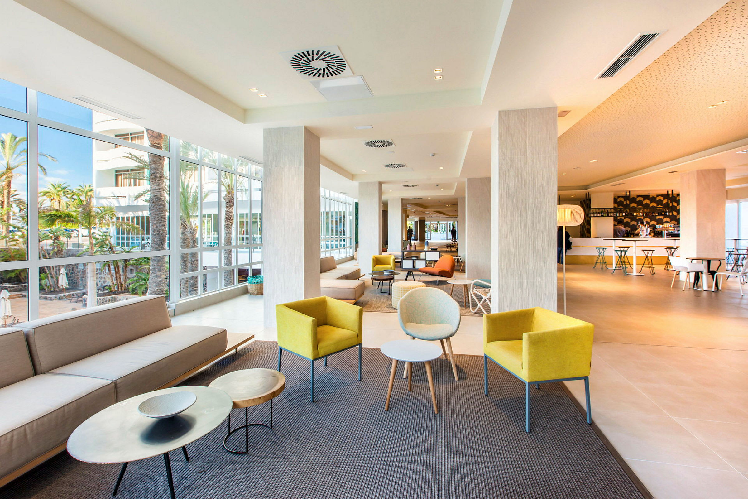 En lys hotellobby med forskjellige sittegrupper og store vinduer. (AI-generert tekst)