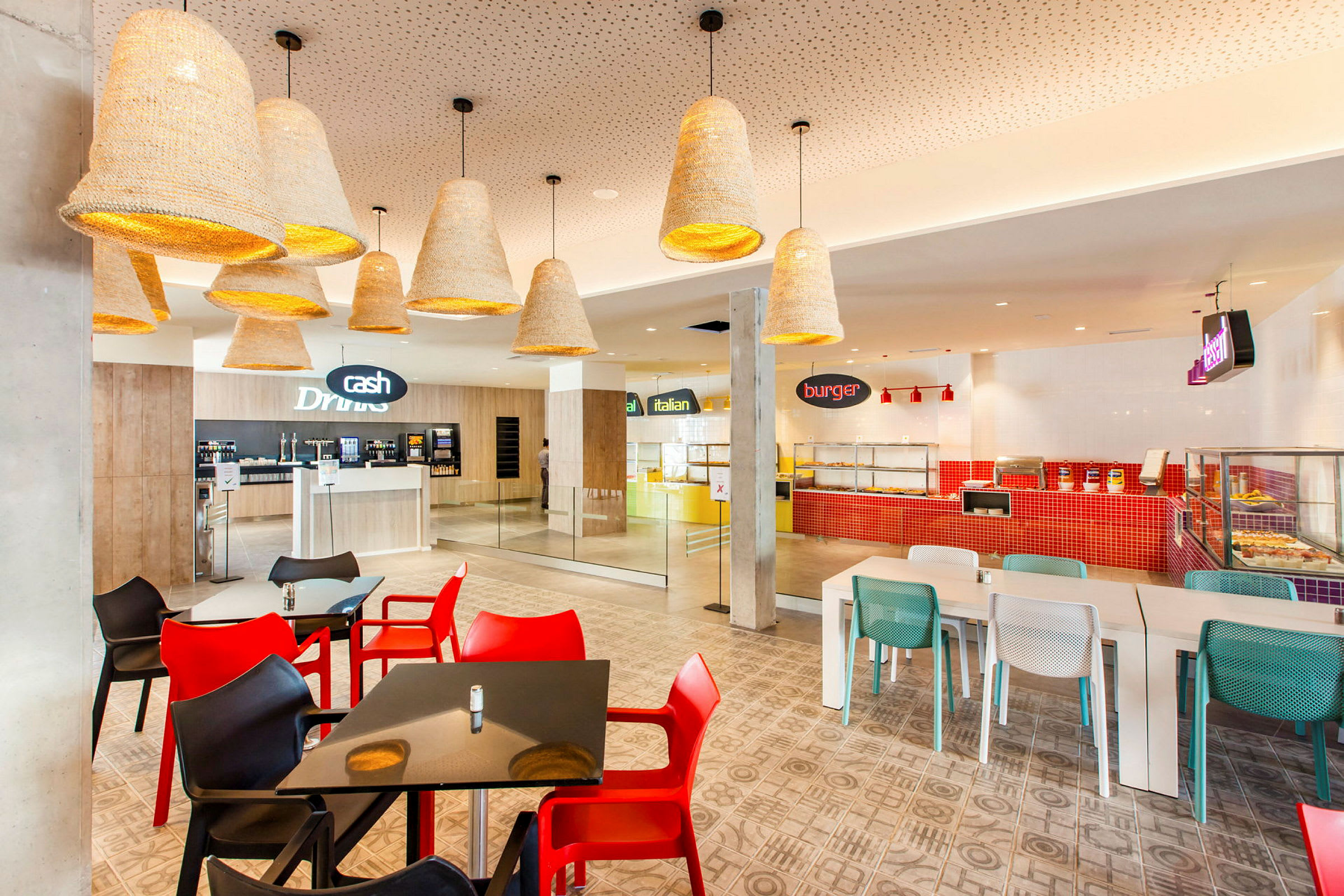 Bilde av en moderne restaurant med fargerike stoler og forskjellige matstasjoner. (AI-generert tekst)