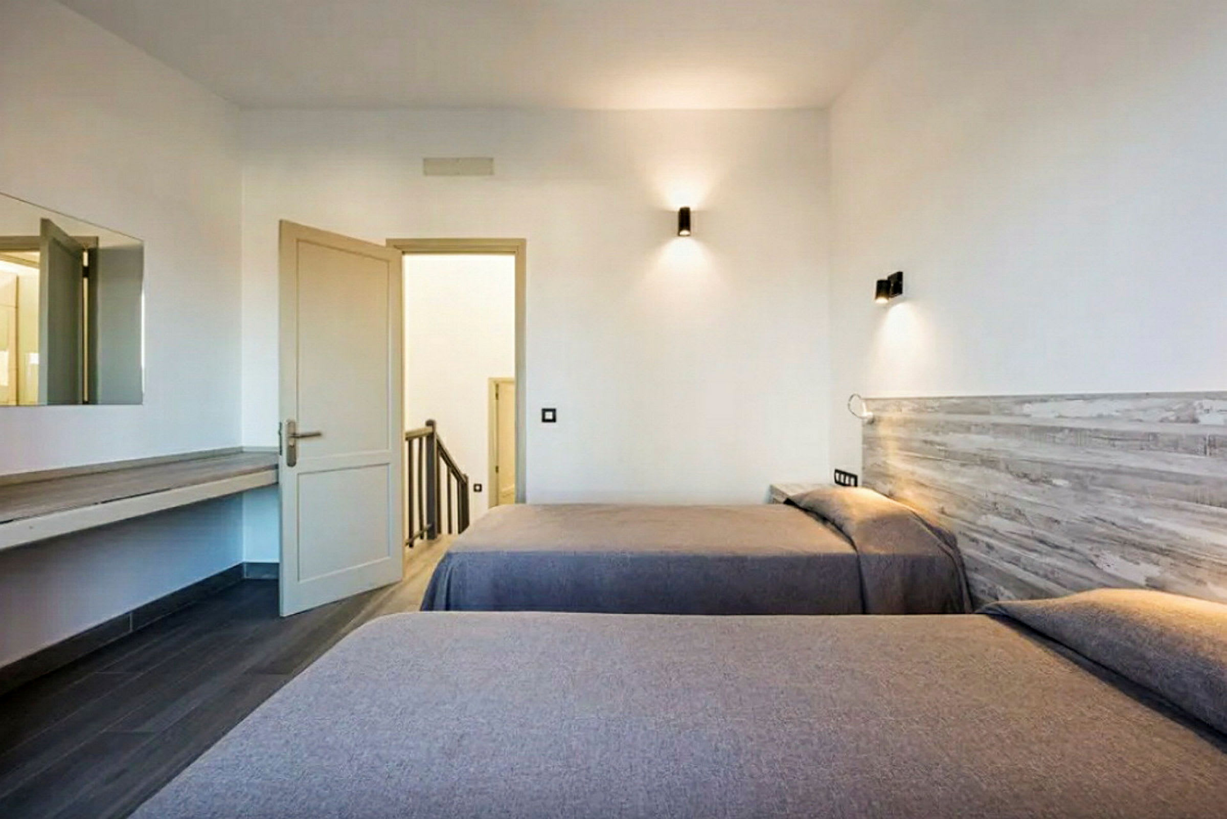 Hotellrom med to enkeltsenger og en åpen dør som fører til en trappeoppgang. (AI-generert tekst)
