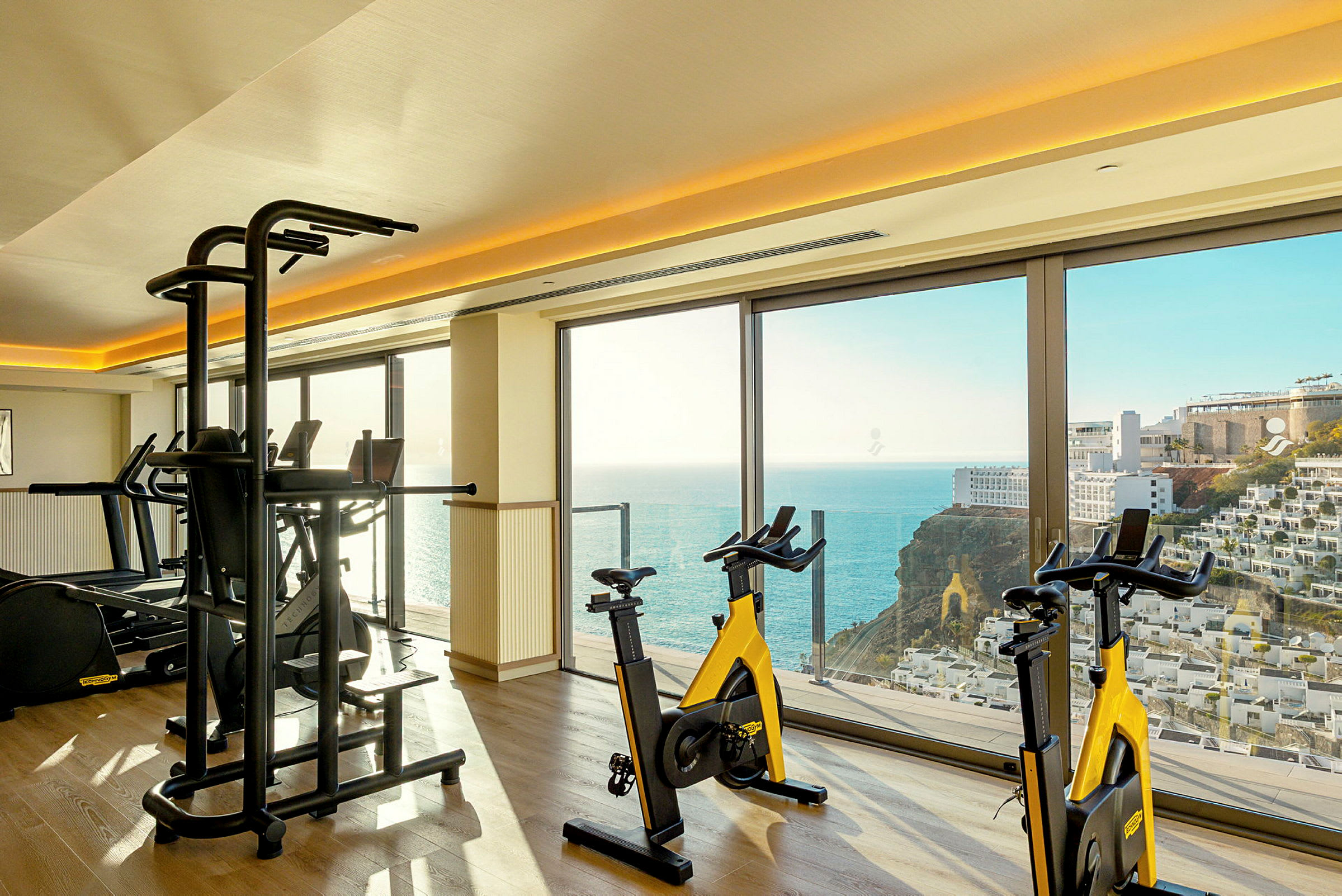 Gym med treningssykler og utsikt over havet. (AI-generert tekst)