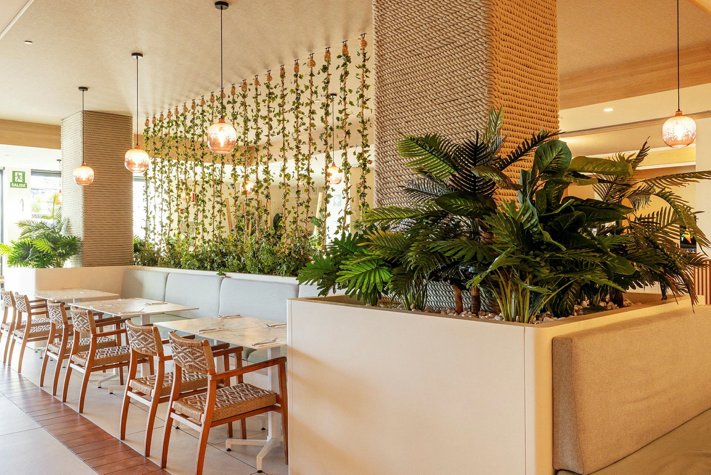 Interiør fra en restaurant med veggdekorasjoner av planter og moderne møbler. (AI-generert tekst)