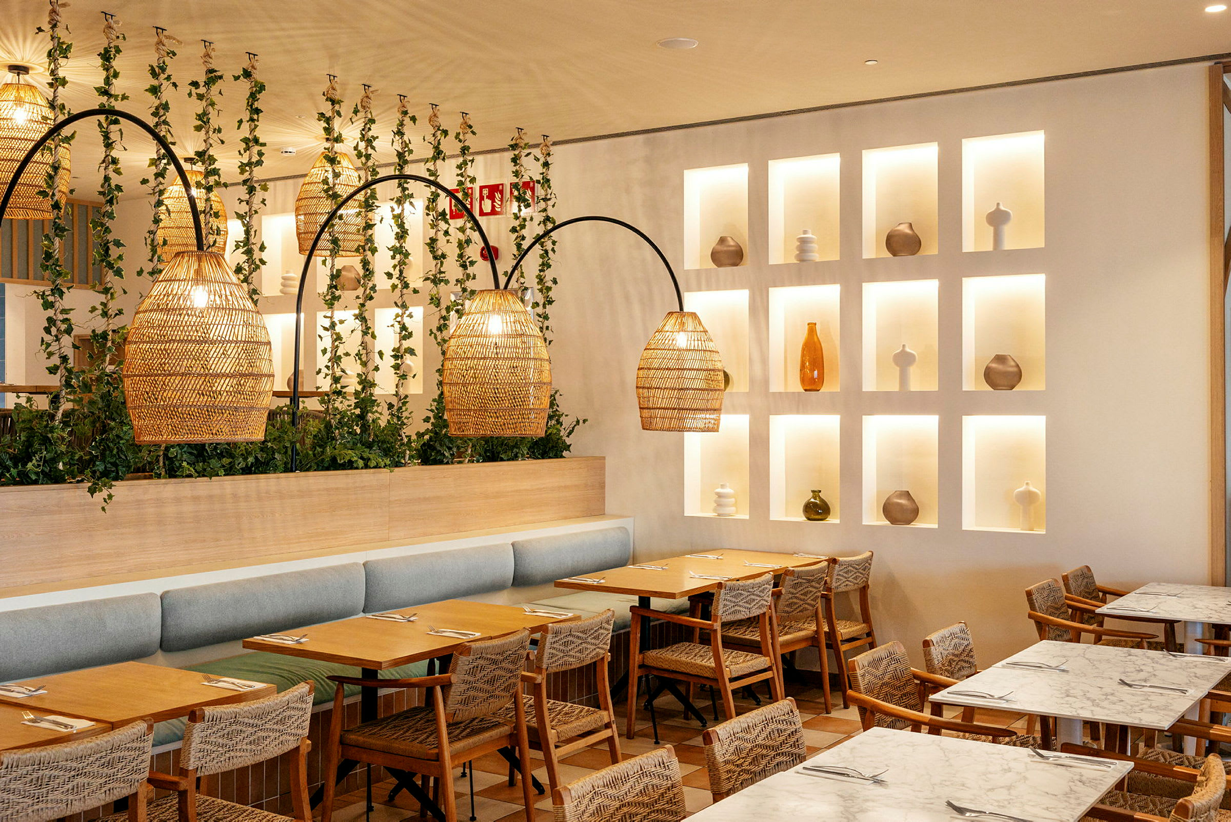 Bilde av et moderne og stilfullt innredet restaurantområde med bord, stoler, plantepynt og dekorative lamper. (AI-generert tekst)