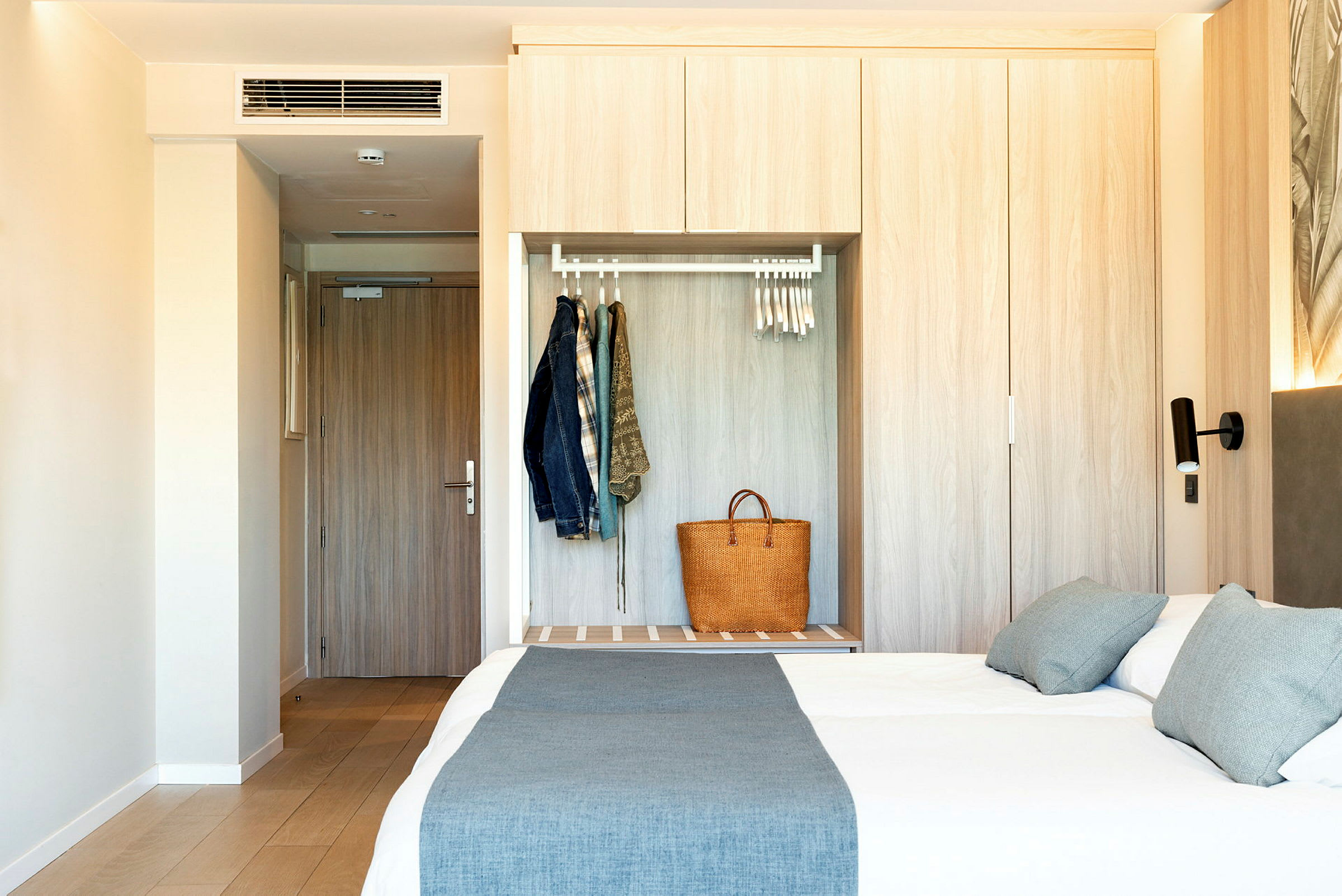 Et hotellrom med en dør, garderobe og en oppredd dobbeltseng. (AI-generert tekst)