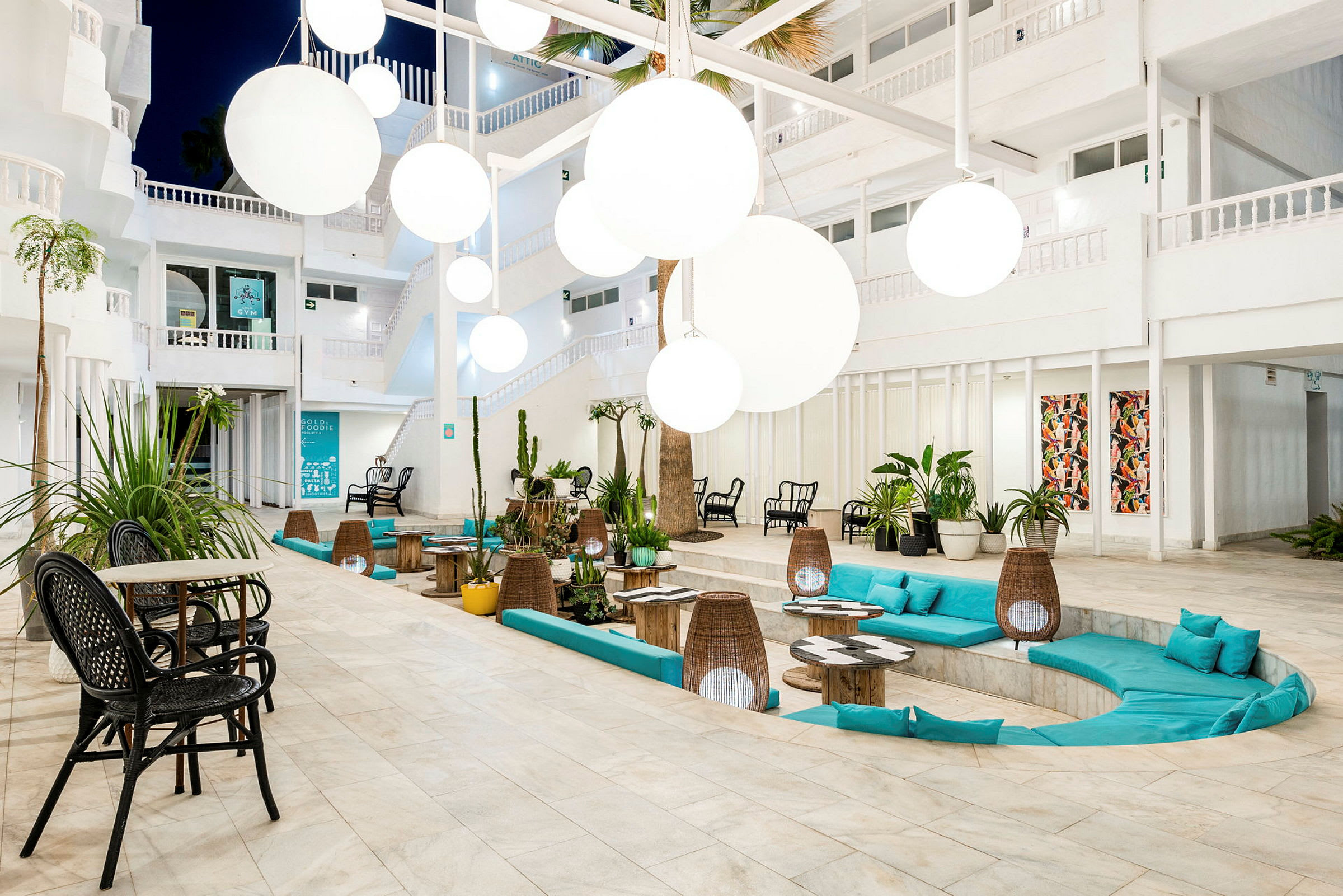En lys og moderne lounge med sirkulære sofaer, fargerike puter og store hvite hengende lamper. (AI-generert tekst)