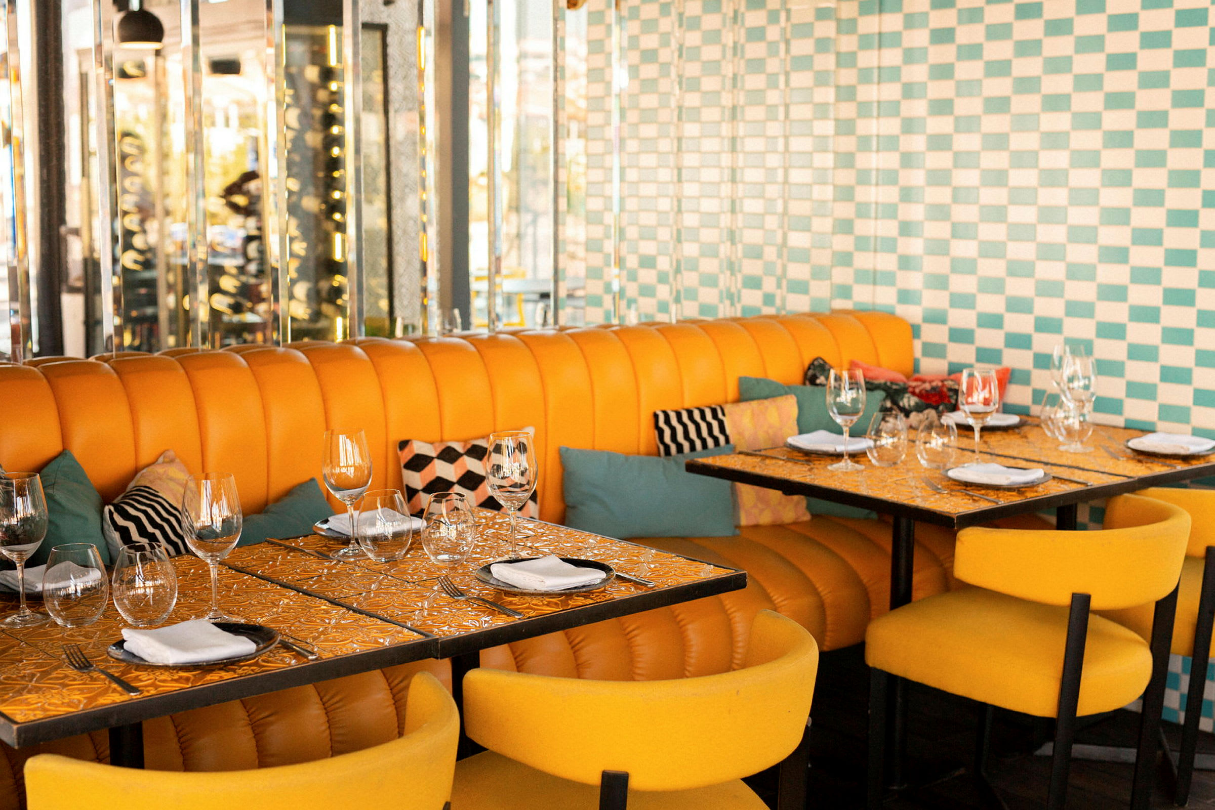 Restaurantmiljø med oransje stoppede sofaer, gule stoler og dekkede bord. (AI-generert tekst)