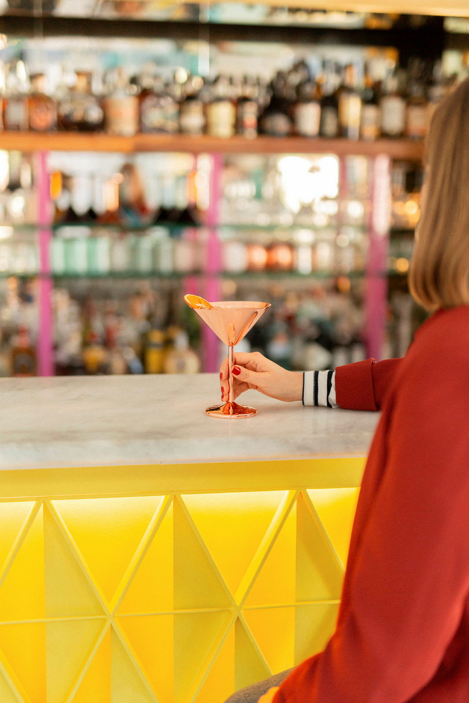 En person holder et glass på en bar. (AI-generert tekst)