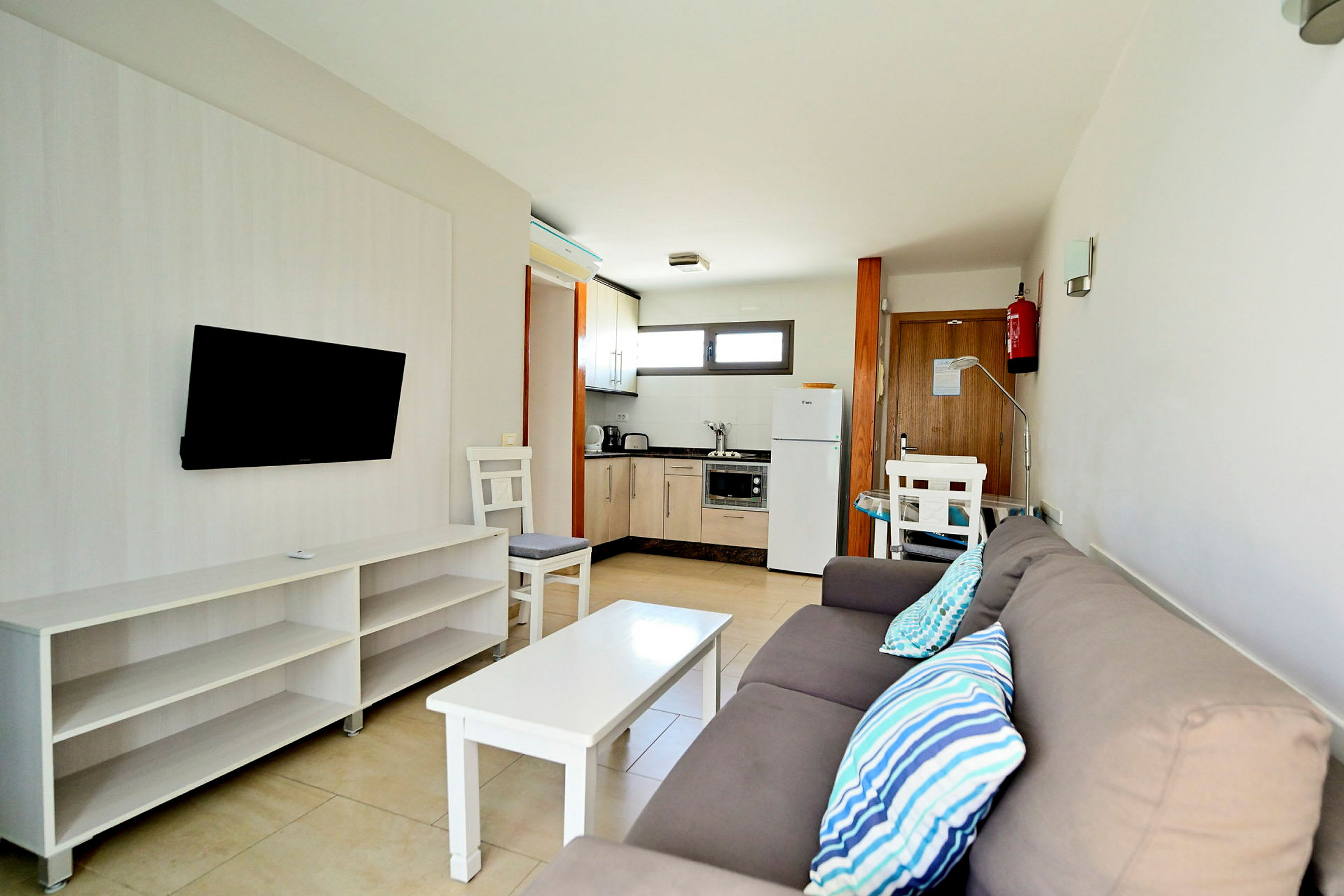 En moderne hotellromsleilighet med sofa, TV, bord og kjøkken. (AI-generert tekst)