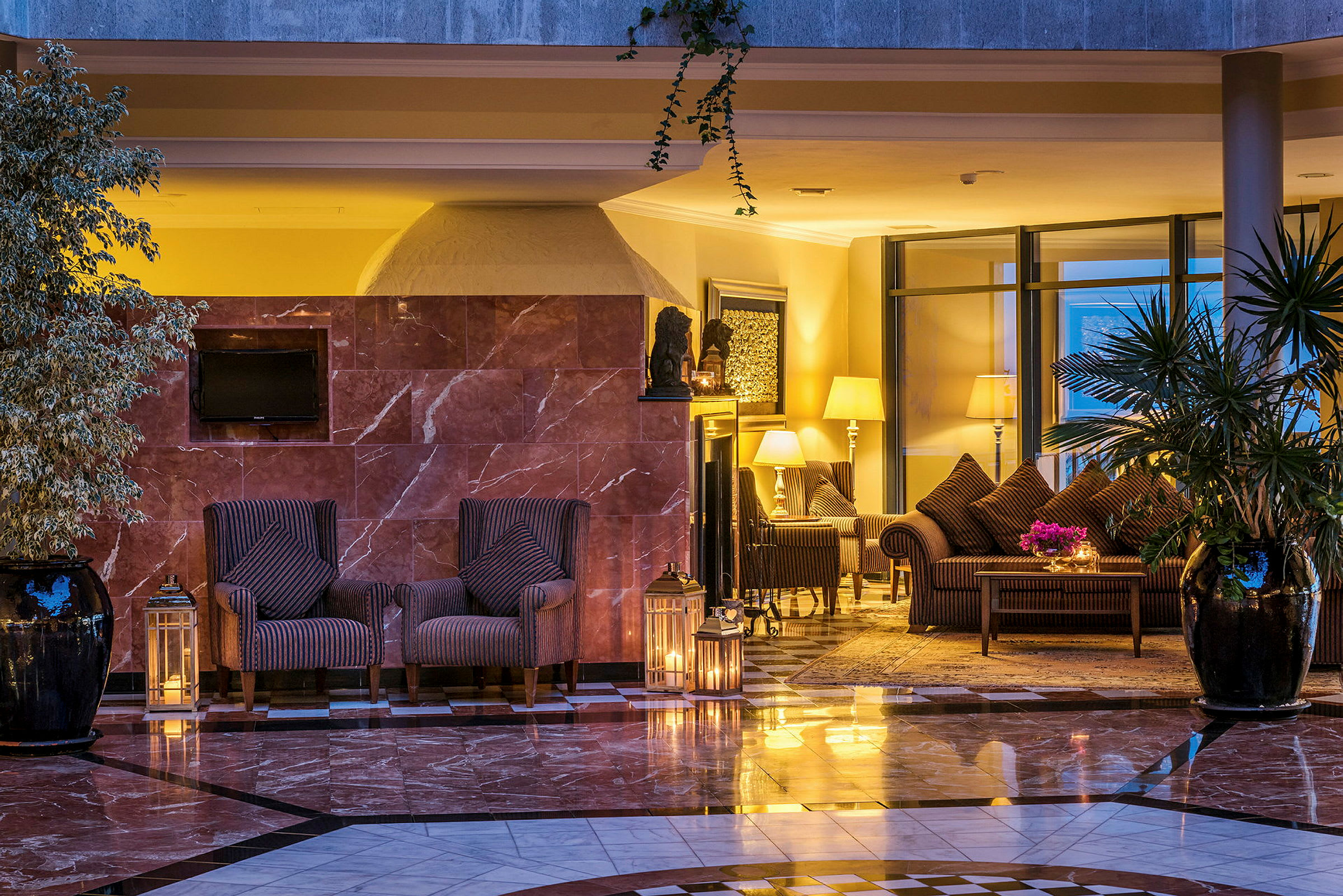 Et hotellrom med elegant innredning, inkludert lenestoler, bord, lampeskjermer og planter. (AI-generert tekst)