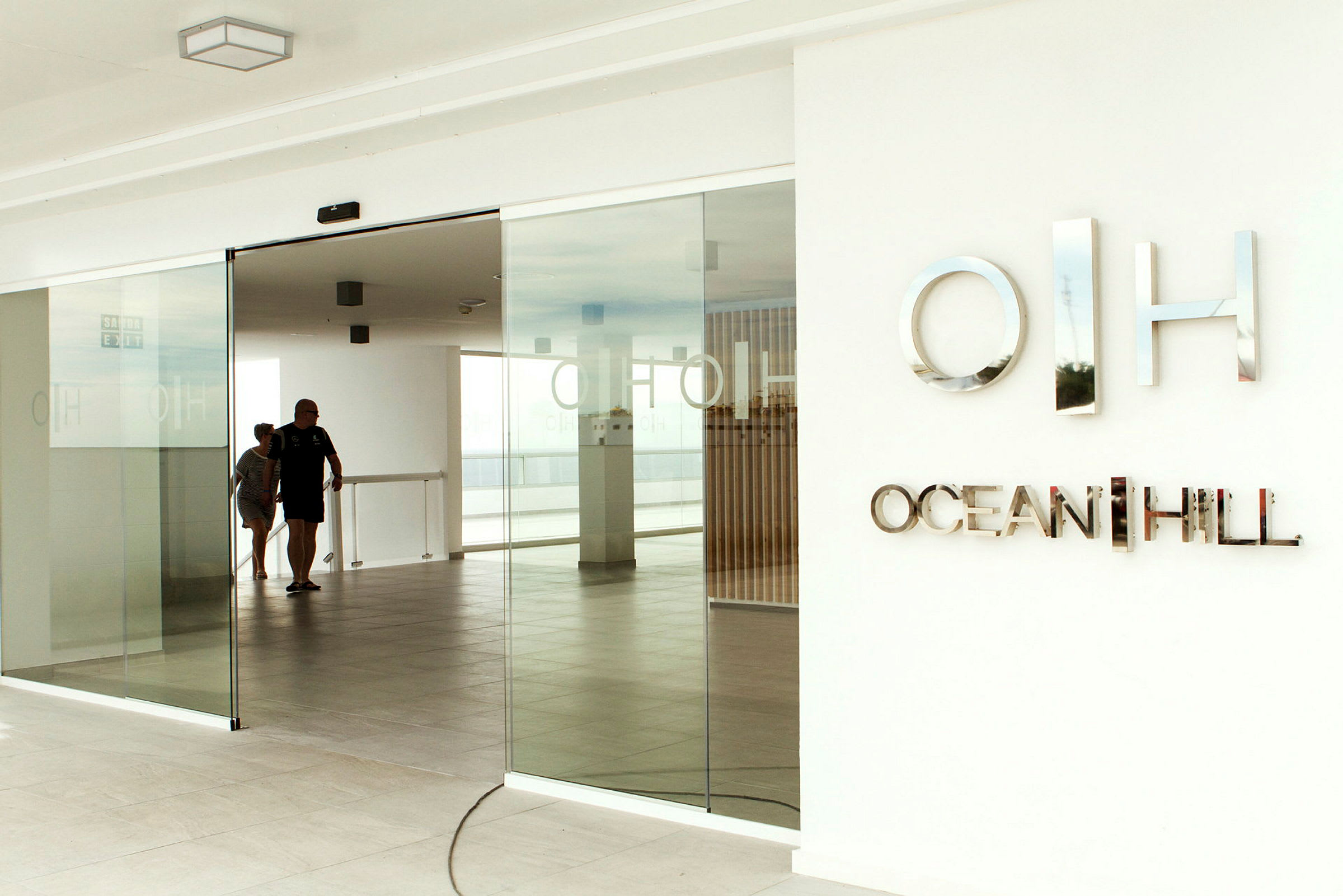 Inngang med glassdører og skiltet 'Ocean Hill'. (AI-generert tekst)